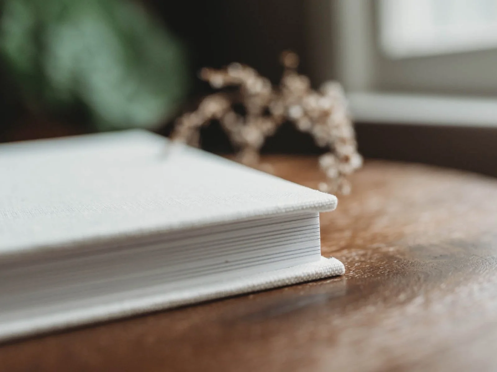 side view of professional photography album with creamy white linen cover and thick pages