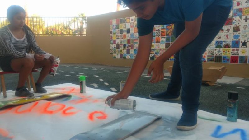 YASC members Irma Mateo, 14 (left), and Jose Arguello, 14, paint on donated skateboards to be used in a community planning event at a vacant lot in Santa Ana. Image: Kristopher Fortin