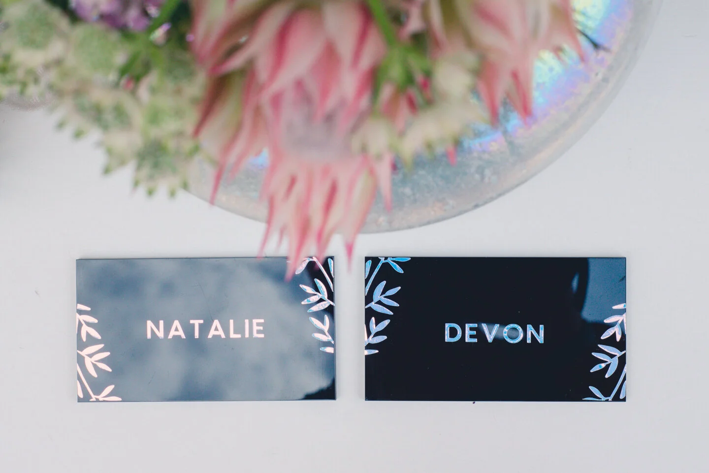 Black acrylic place cards with holographic vinyl and floral elements.