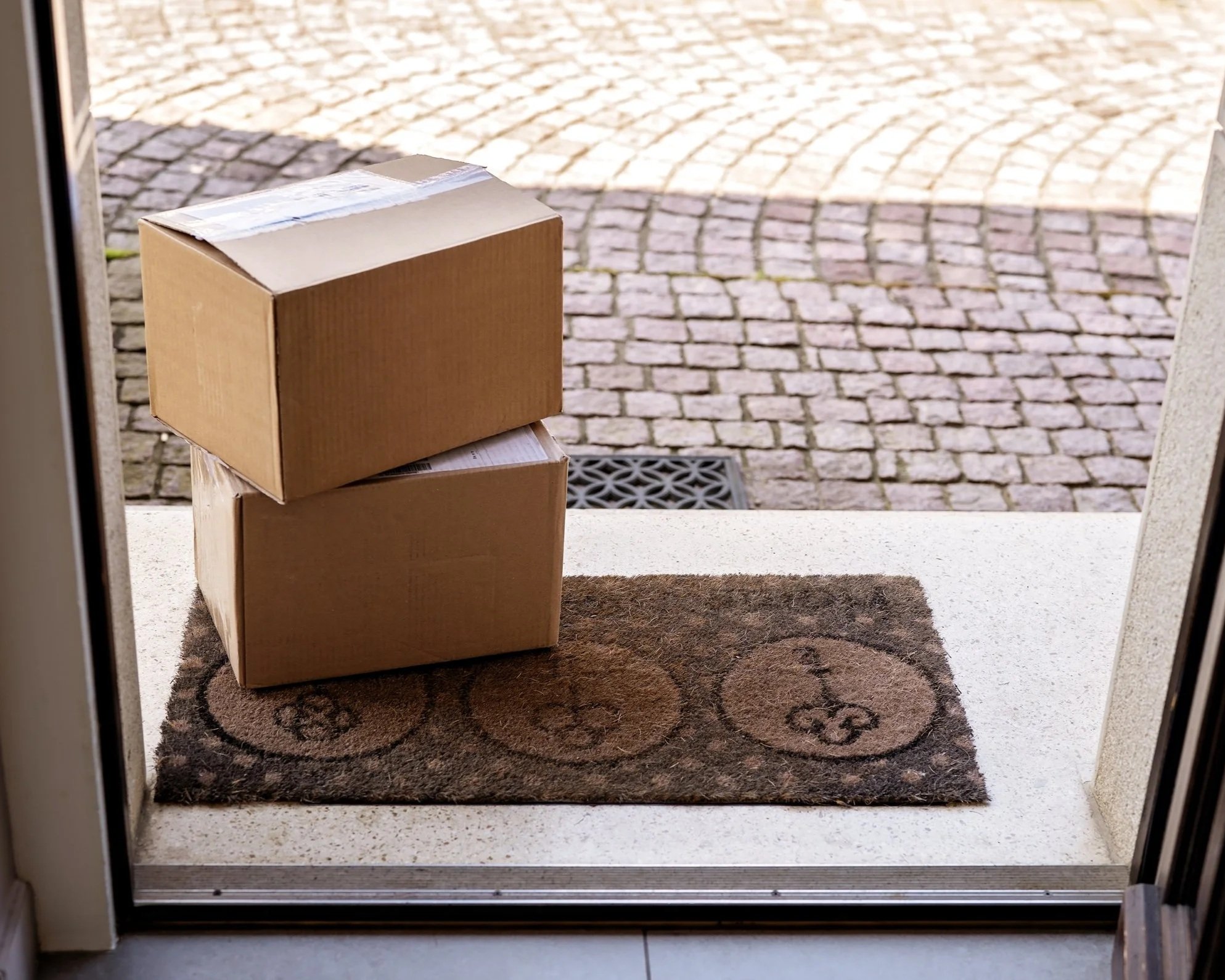 Two boxes stacked and sitting at a customers doorstep.