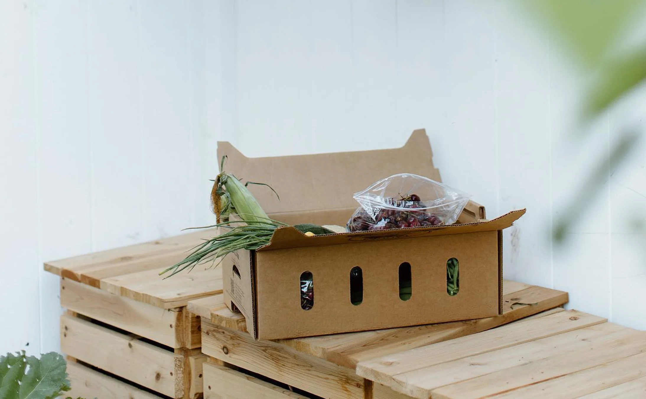 A box sitting on a wooden crate filled with farm fresh produce and berries