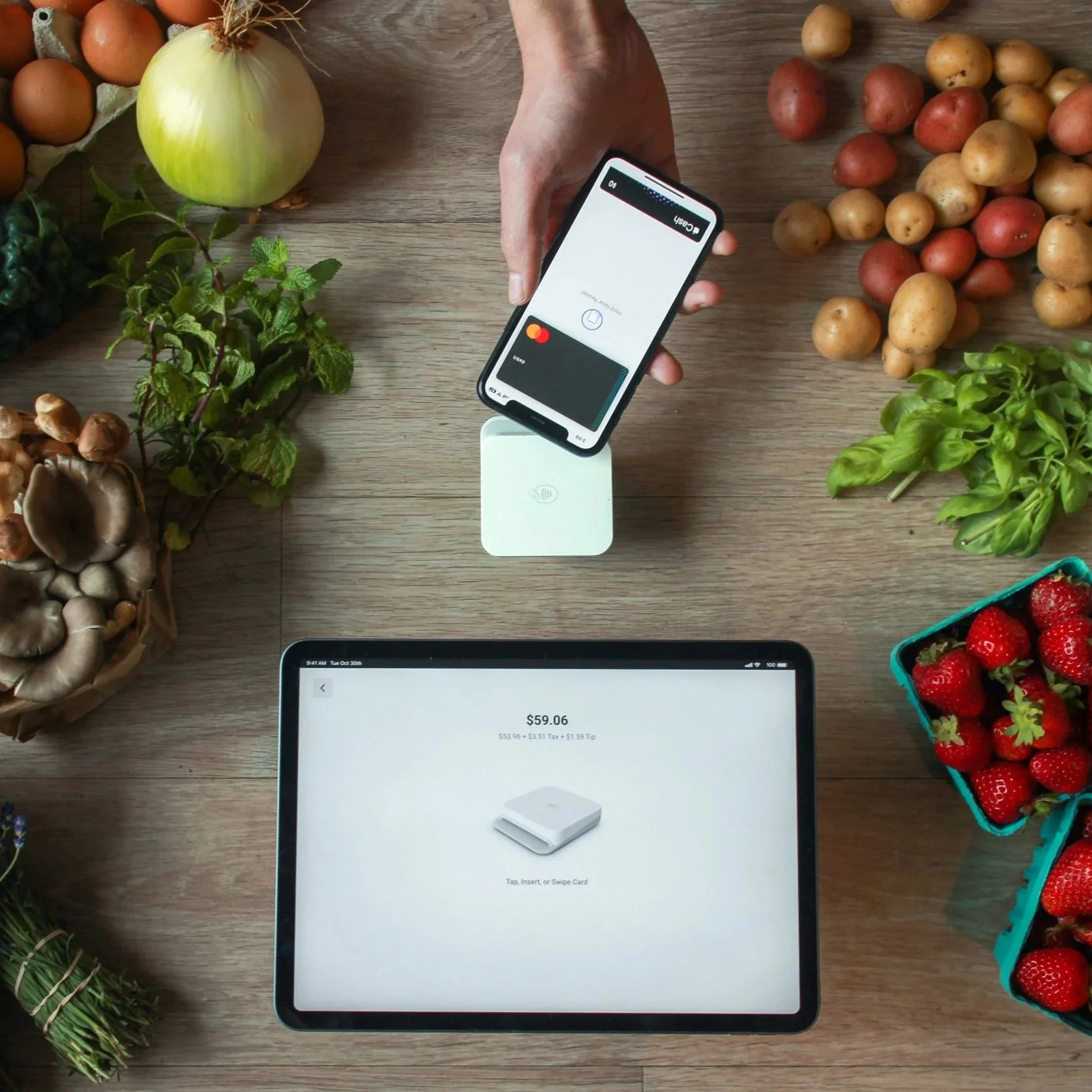 A customer using applepay to purchase produce from a farmer at a farm stand