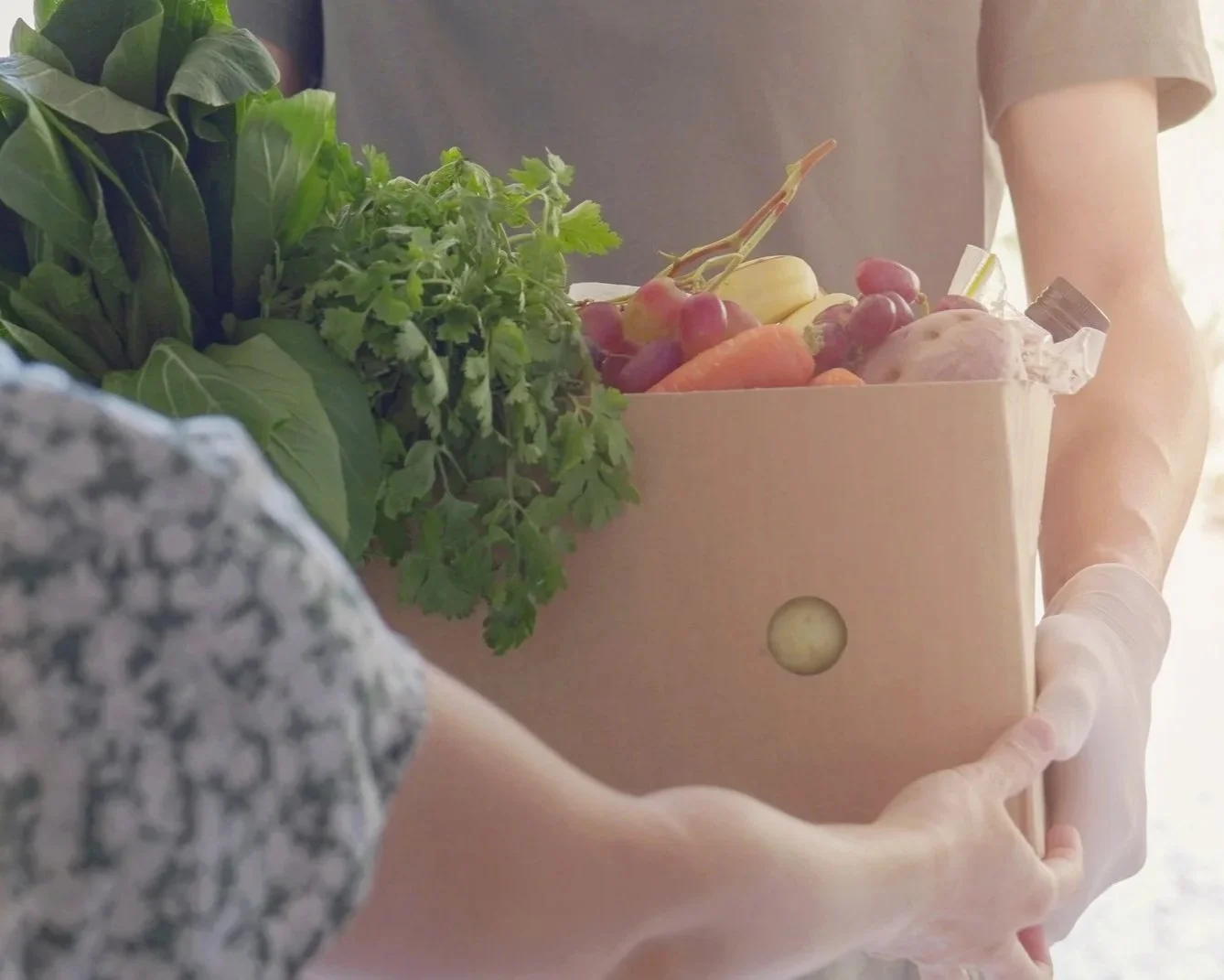 A driver handing a buyer a box of fresh produce through a Farm delivery service