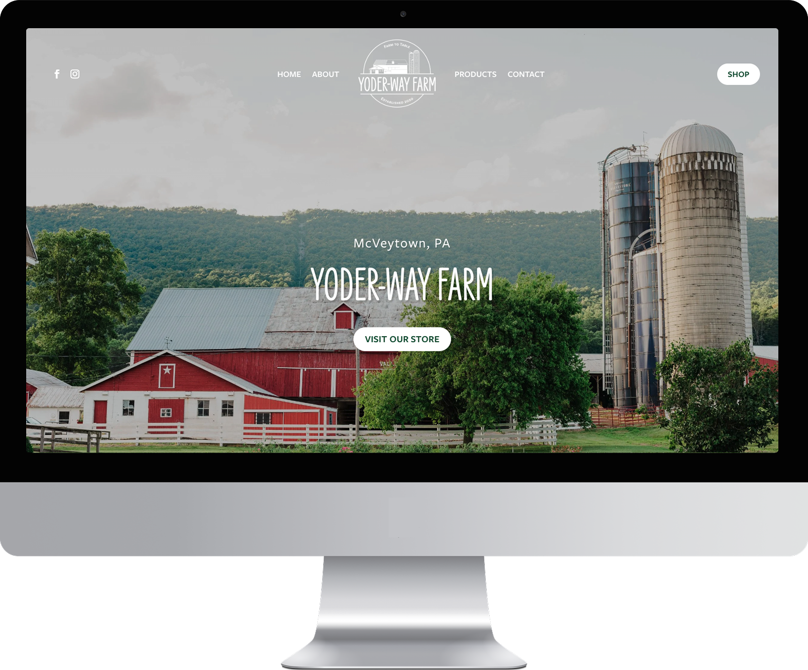Desktop monitor displaying the homepage of the Yoder-Way Farm website, featuring a red barn and silos.