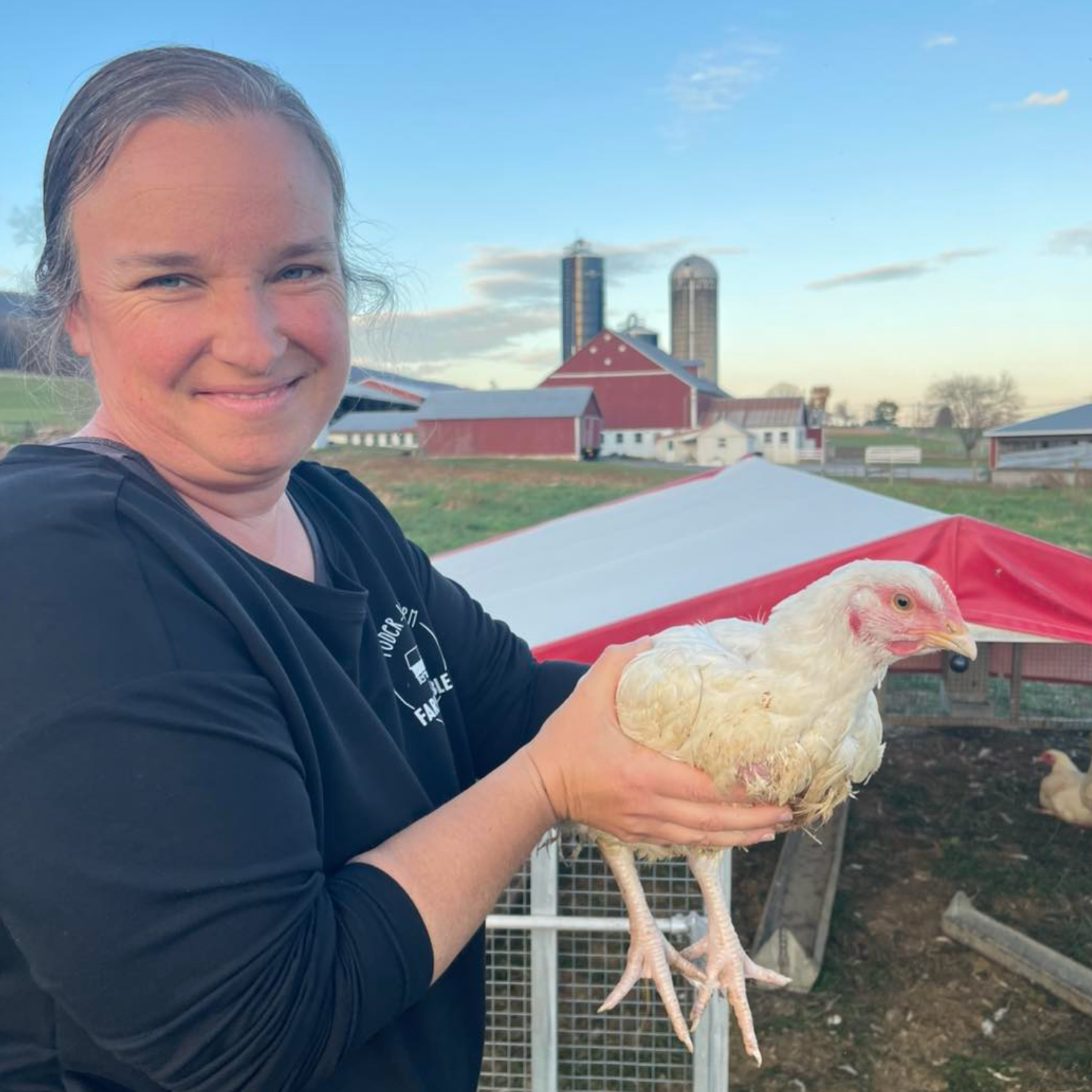 An independent farmer holding a chicken