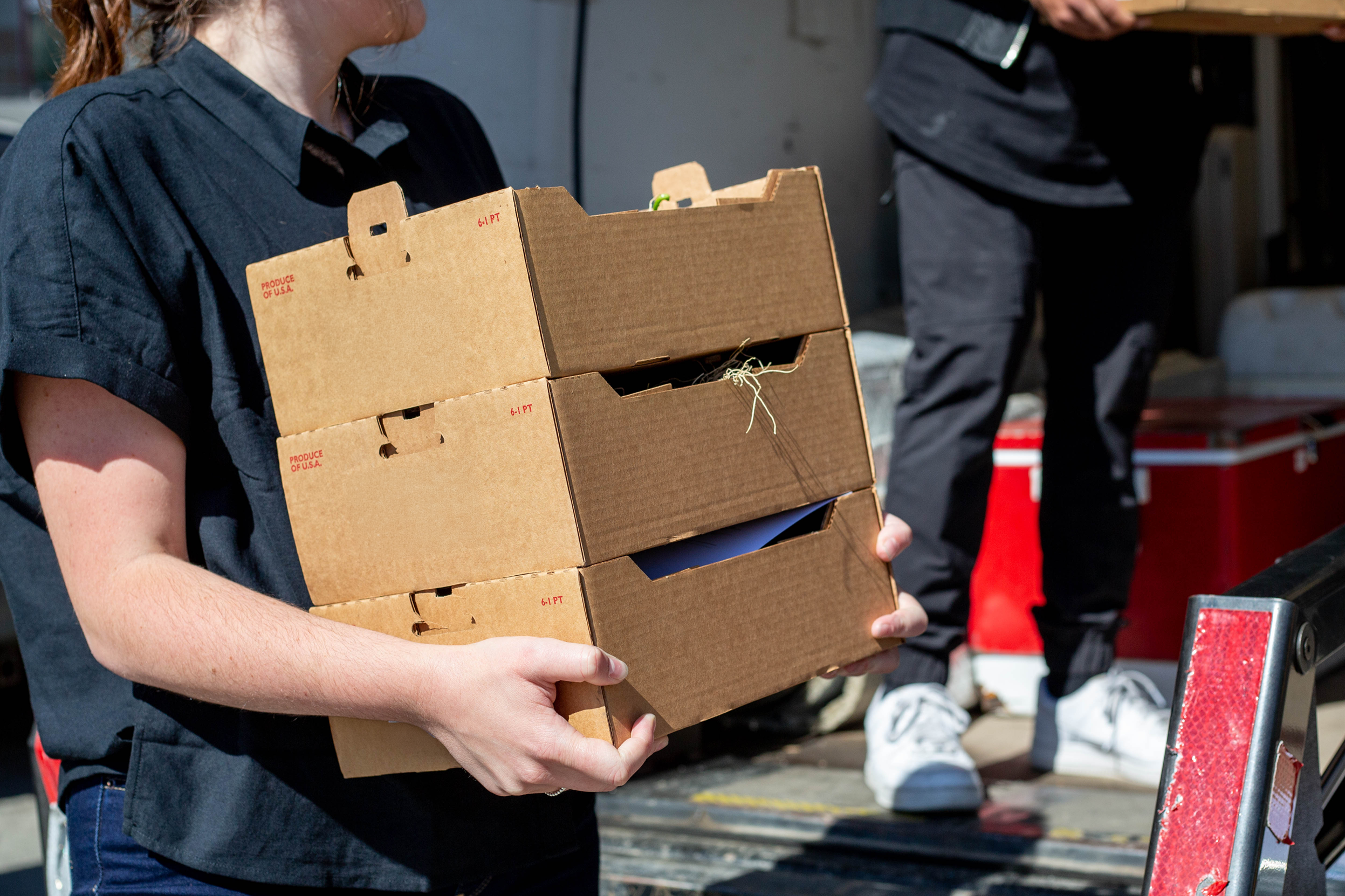 A delivery person carrying multiple boxes of produce