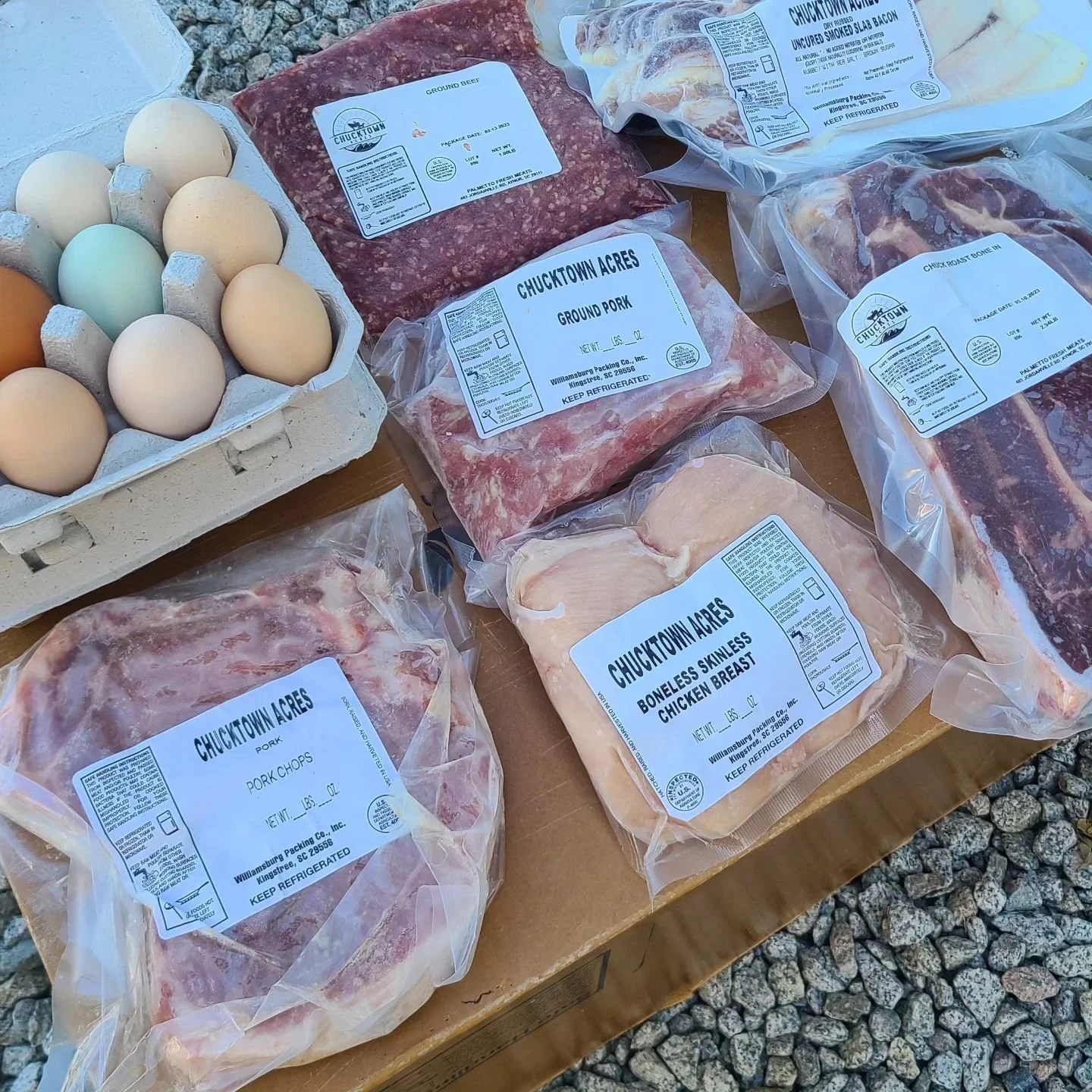 A variety of vacuum-sealed meat products including ground beef, pork chops, and chicken breast from Chucktown Acres, alongside a carton of farm-fresh eggs.