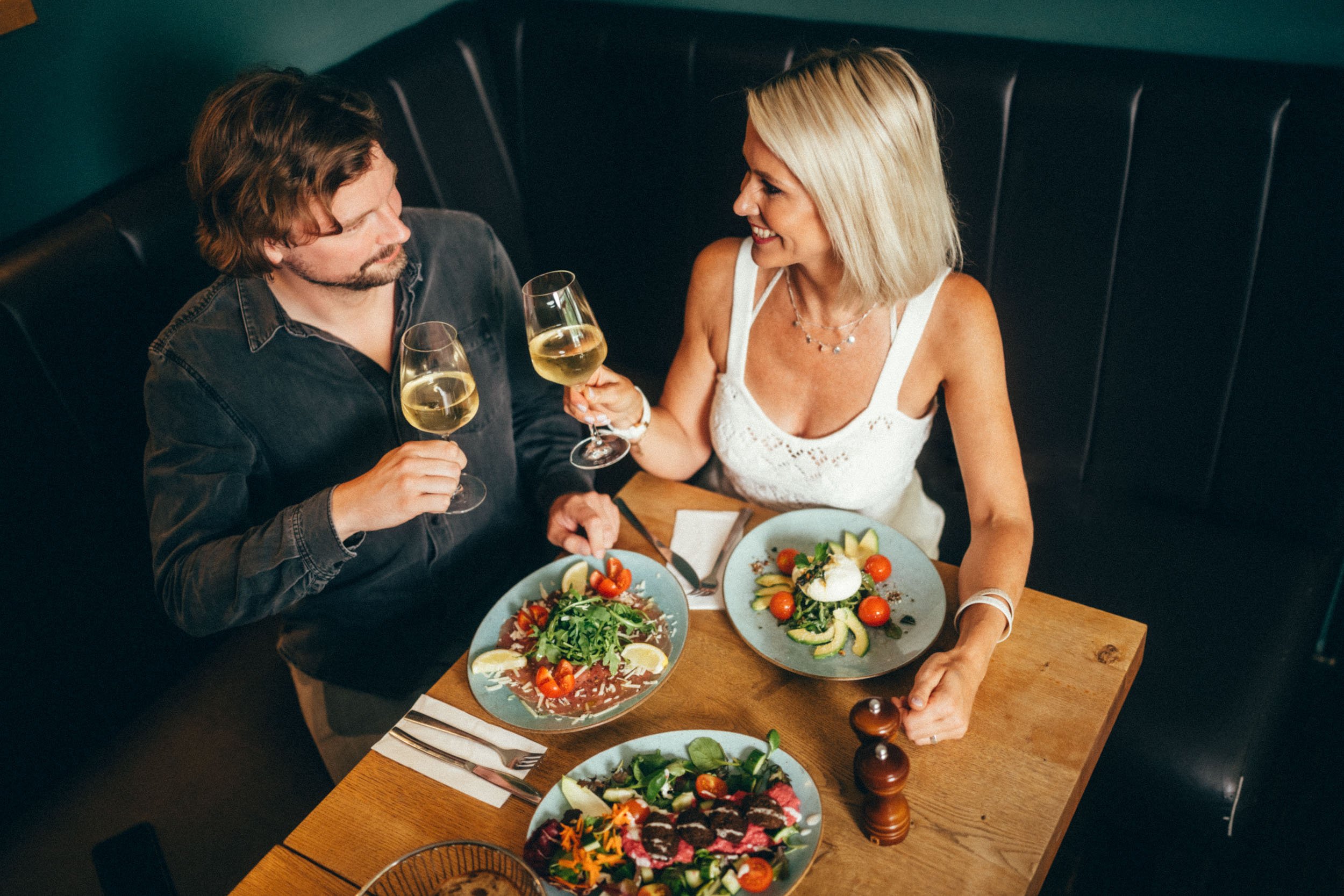Restaurantfotografie eines Paares, das bei gehobenen Speisen und edlem Wein in elegantem Ambiente ein besonderes Date genießt – perfekt, um das luxuriöse Dining-Erlebnis und das stilvolle Ambiente des Restaurants hervorzuheben.