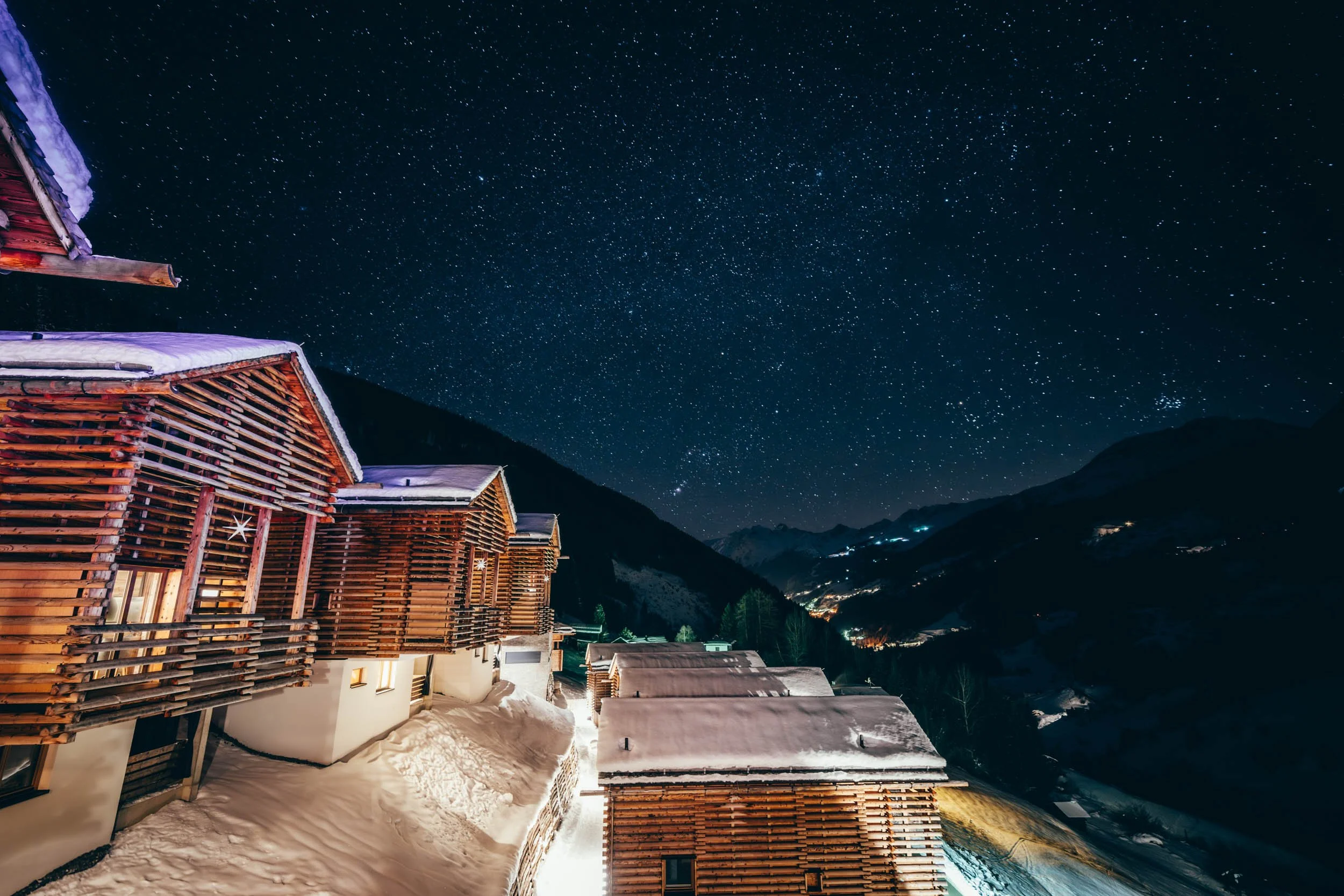 Stimmungsvolle Fotografie eines Berghotels bei Nacht, beleuchtet unter einem klaren Sternenhimmel – ideal, um die majestätische Lage und die einladende Atmosphäre des Hotels in der Nacht zu präsentieren.
