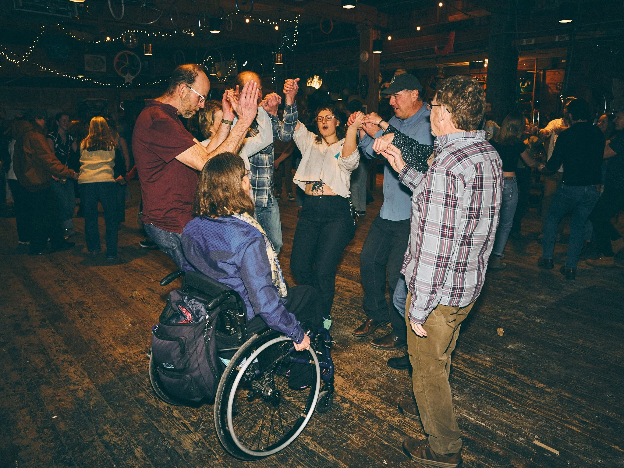 eight participants join hands in a circle. One participant is in a wheelchair.