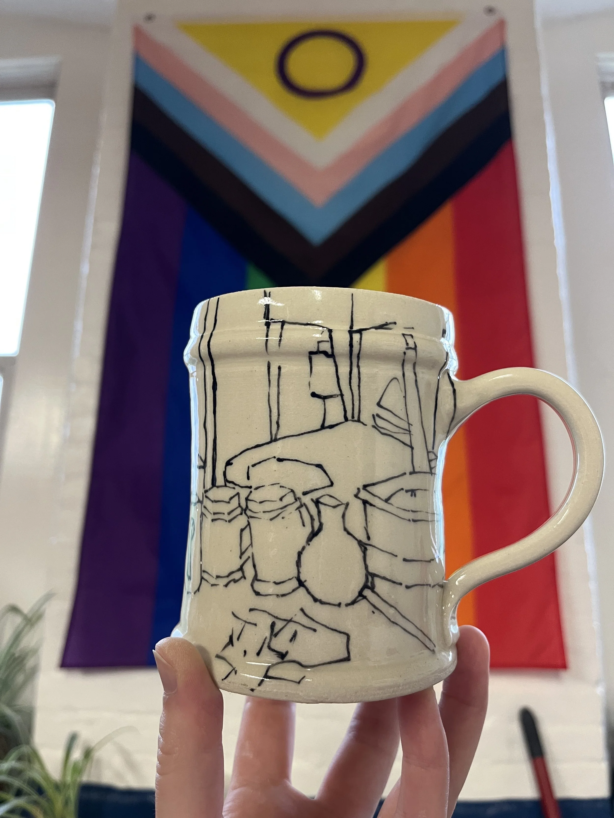 A ceramic mug with a line drawing of a still life scene