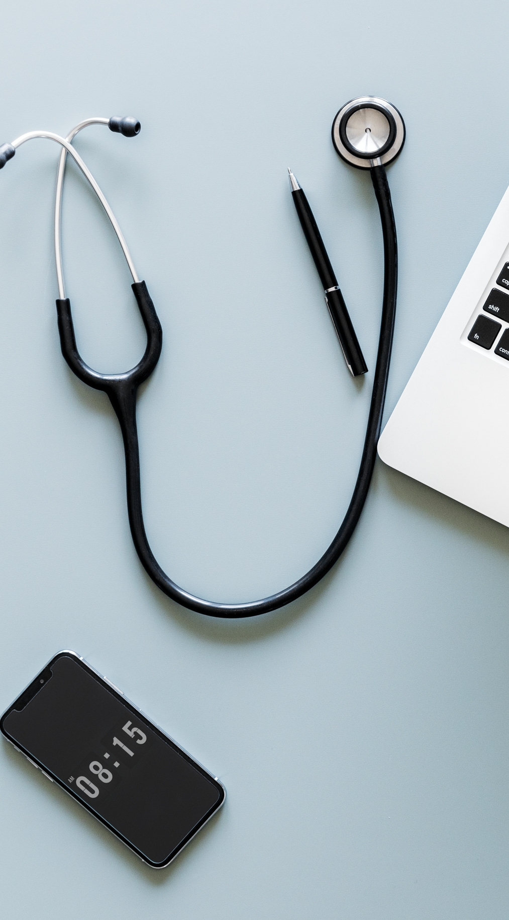 Stethoscope, phone, pen, and laptop on table
