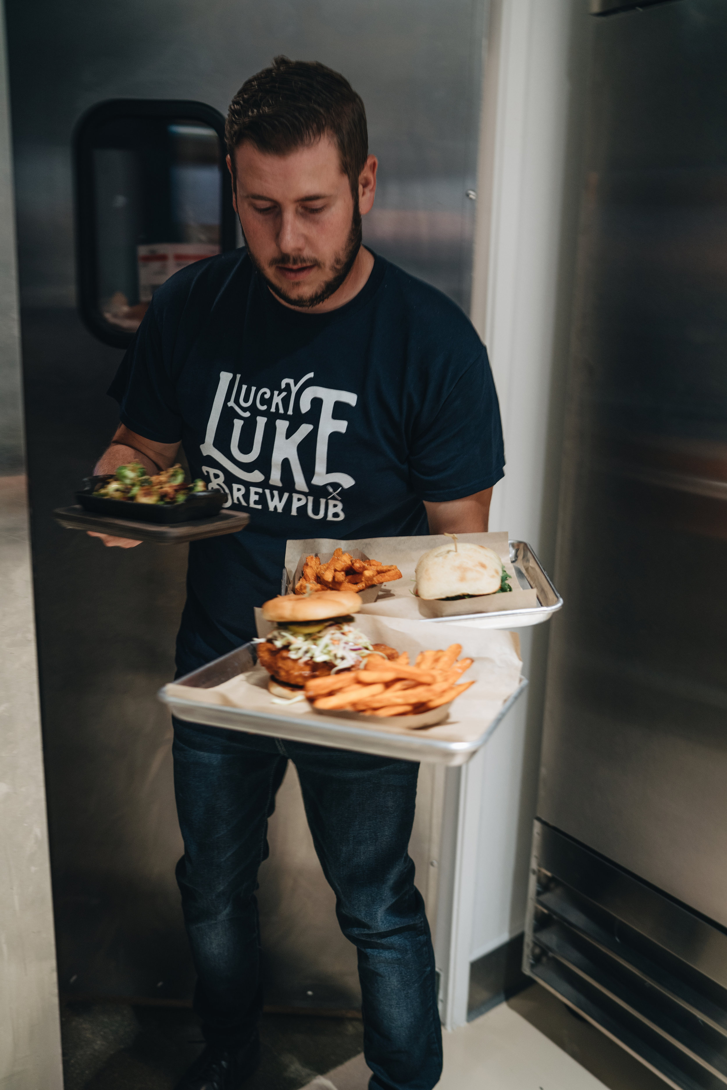  team member braden making his way out of the kitchen with freshly plated sammies and brussels  