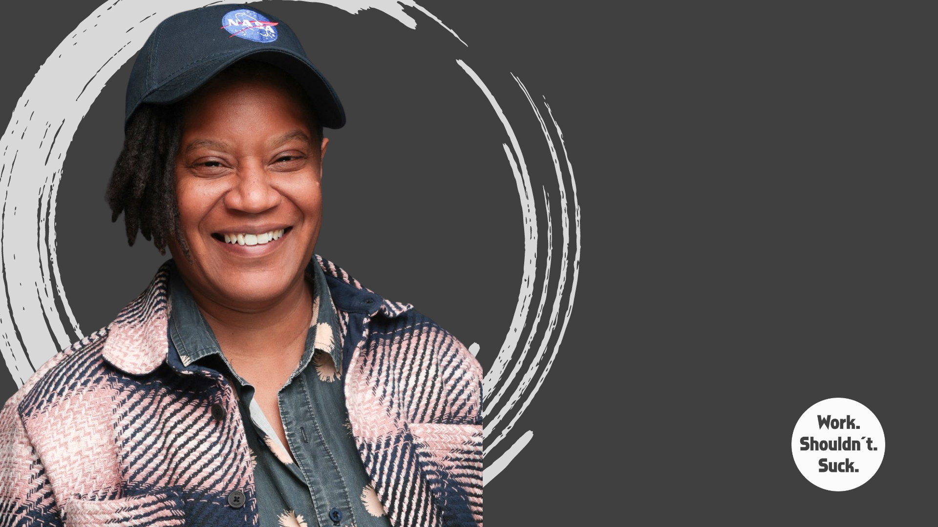 Smiling person wearing a NASA cap and plaid jacket, with a circular brushstroke design and text "Work. Shouldn't. Suck." on a dark background.