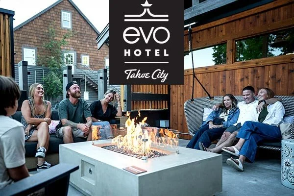 Group of people sitting around a fire pit on a patio at the Evo Hotel in Tahoe City.