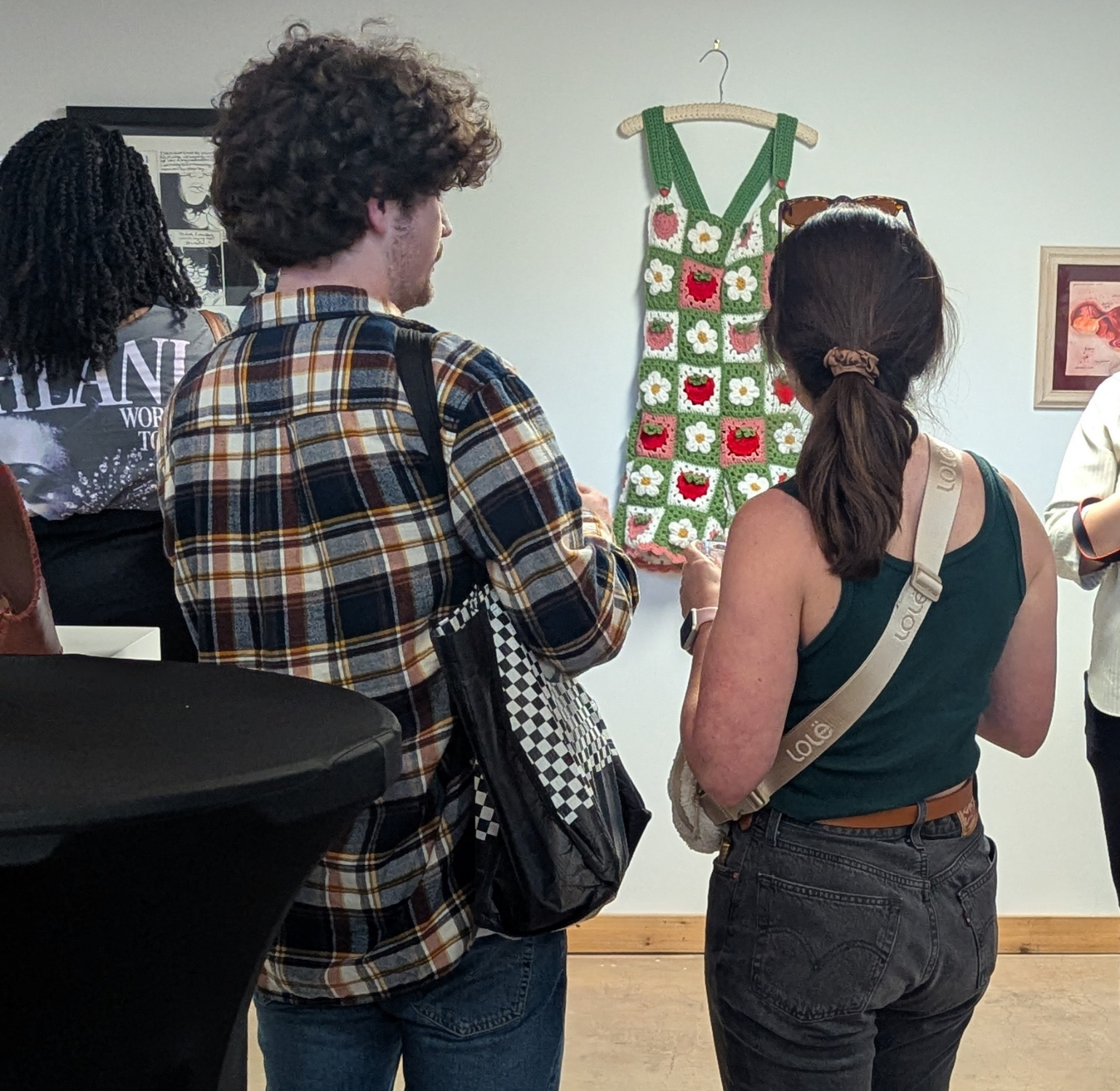 two visitors to the 2025 Art Room Member Exhibition look at art work on display