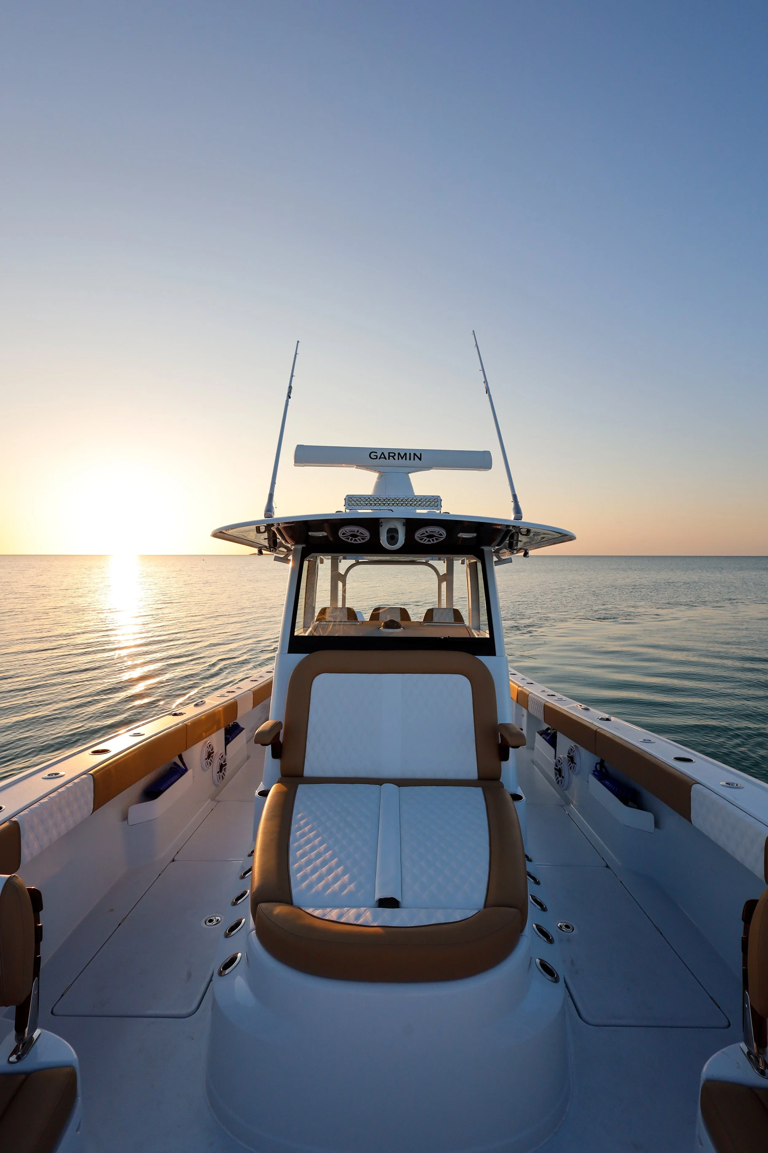 Front view of a boat on calm water at sunset, with seating area and GPS equipment.