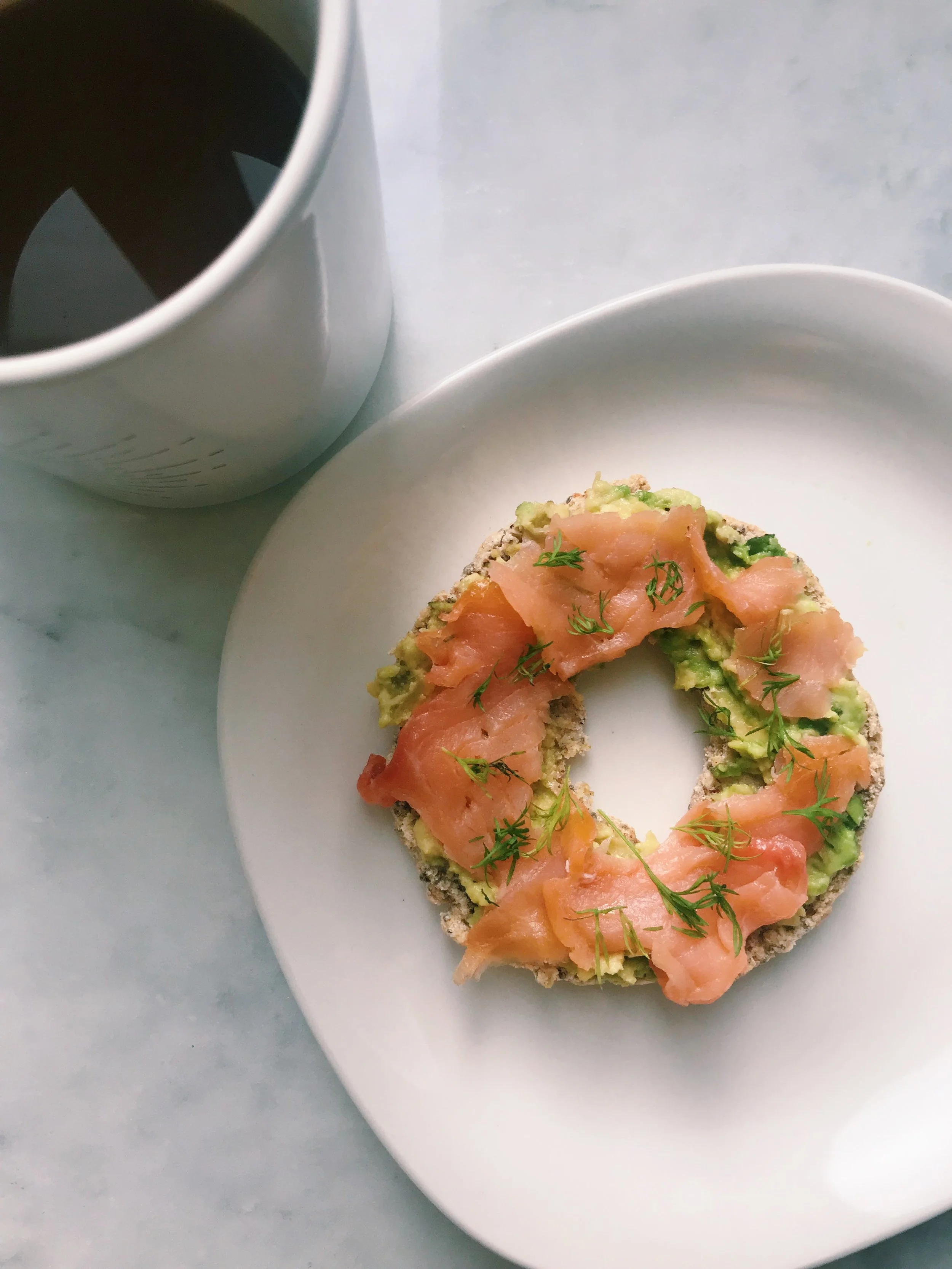 A coconut chia bagel topped with avocado and smoked salmon.
