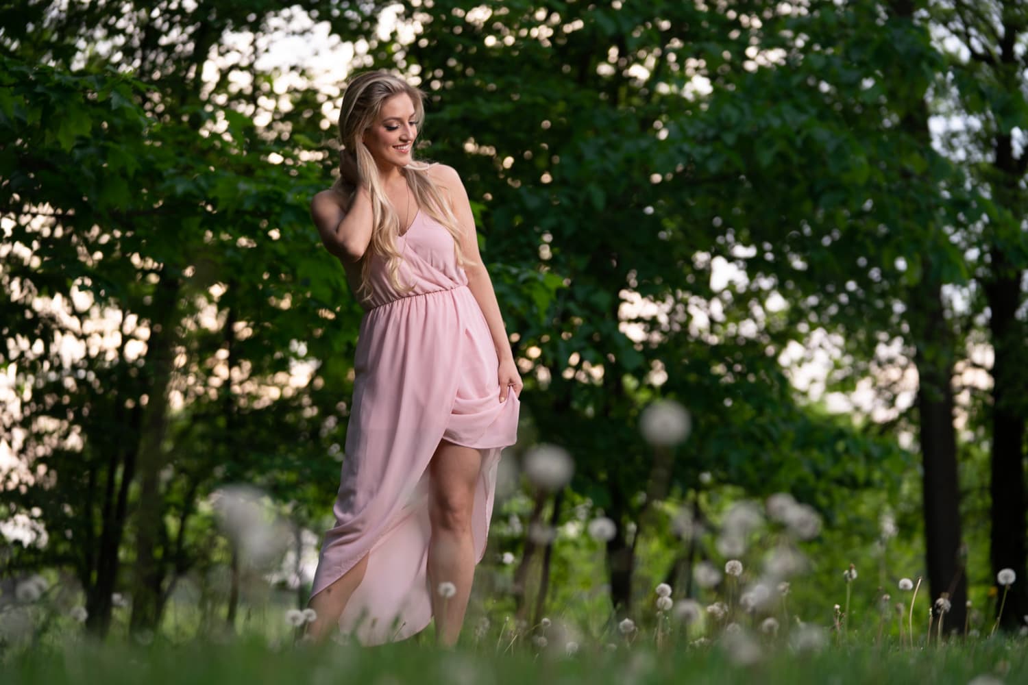  Blonde woman in pink dress standing in woods 
