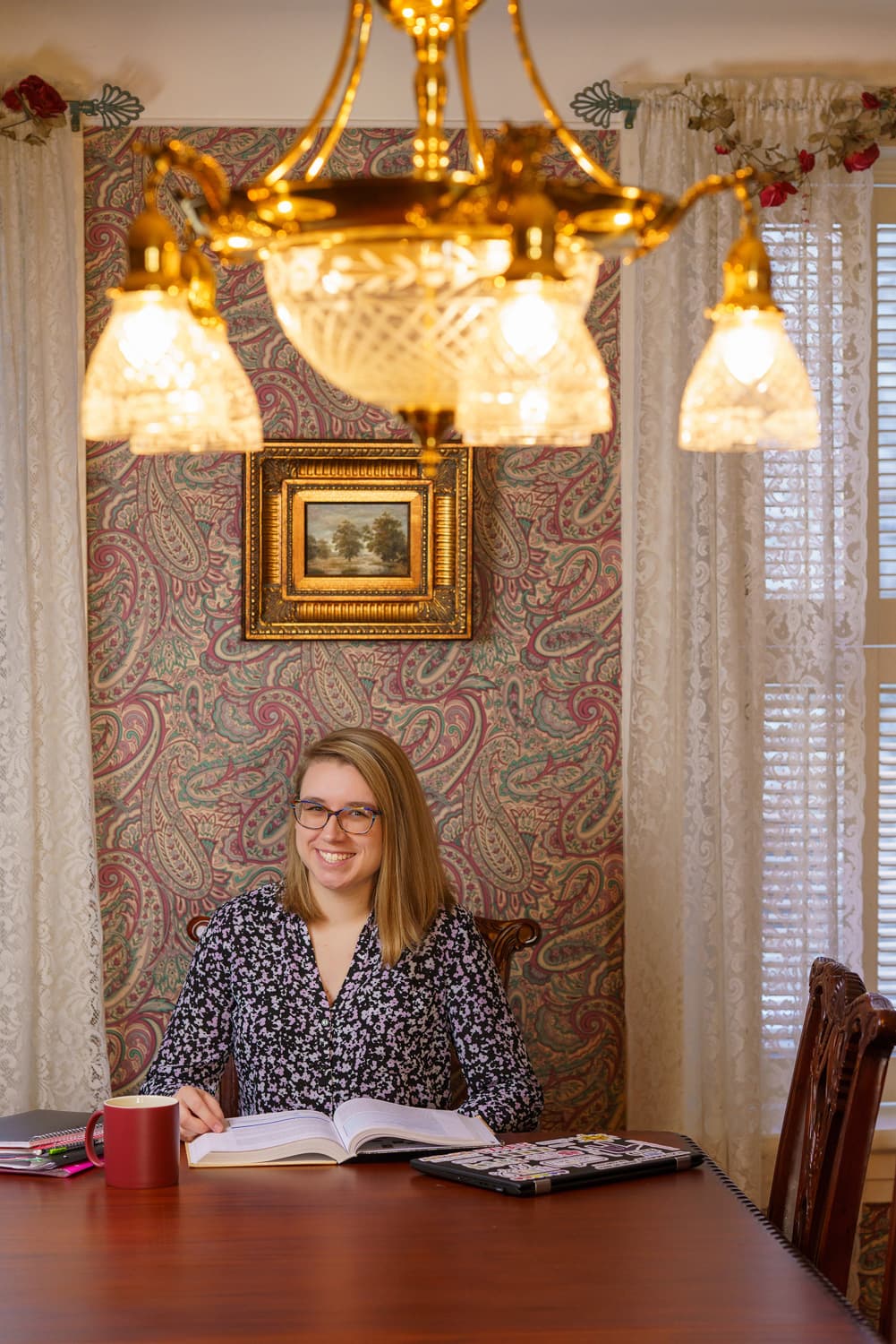  student with coffee underneath chandelier.   