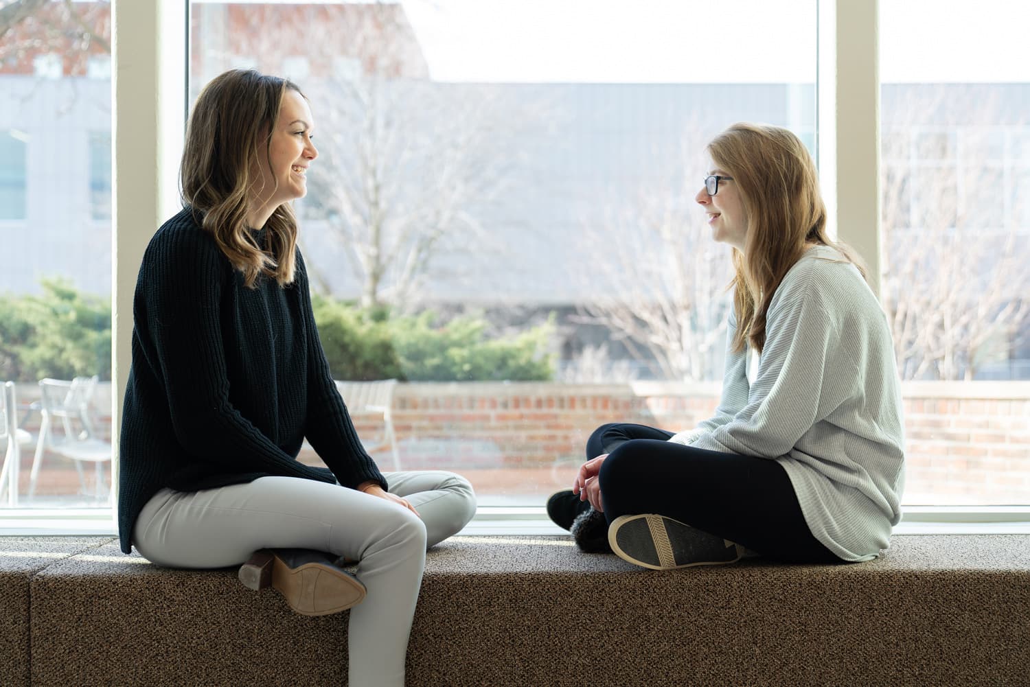  Student and advisor sitting and talking near windows 