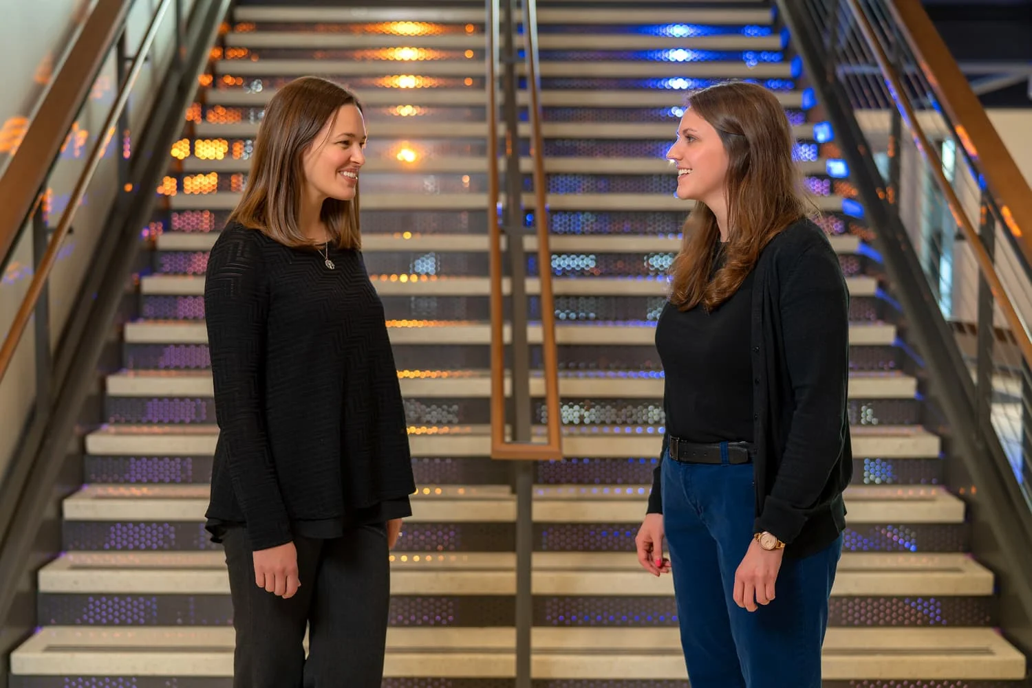 2 women talking in front of stairs