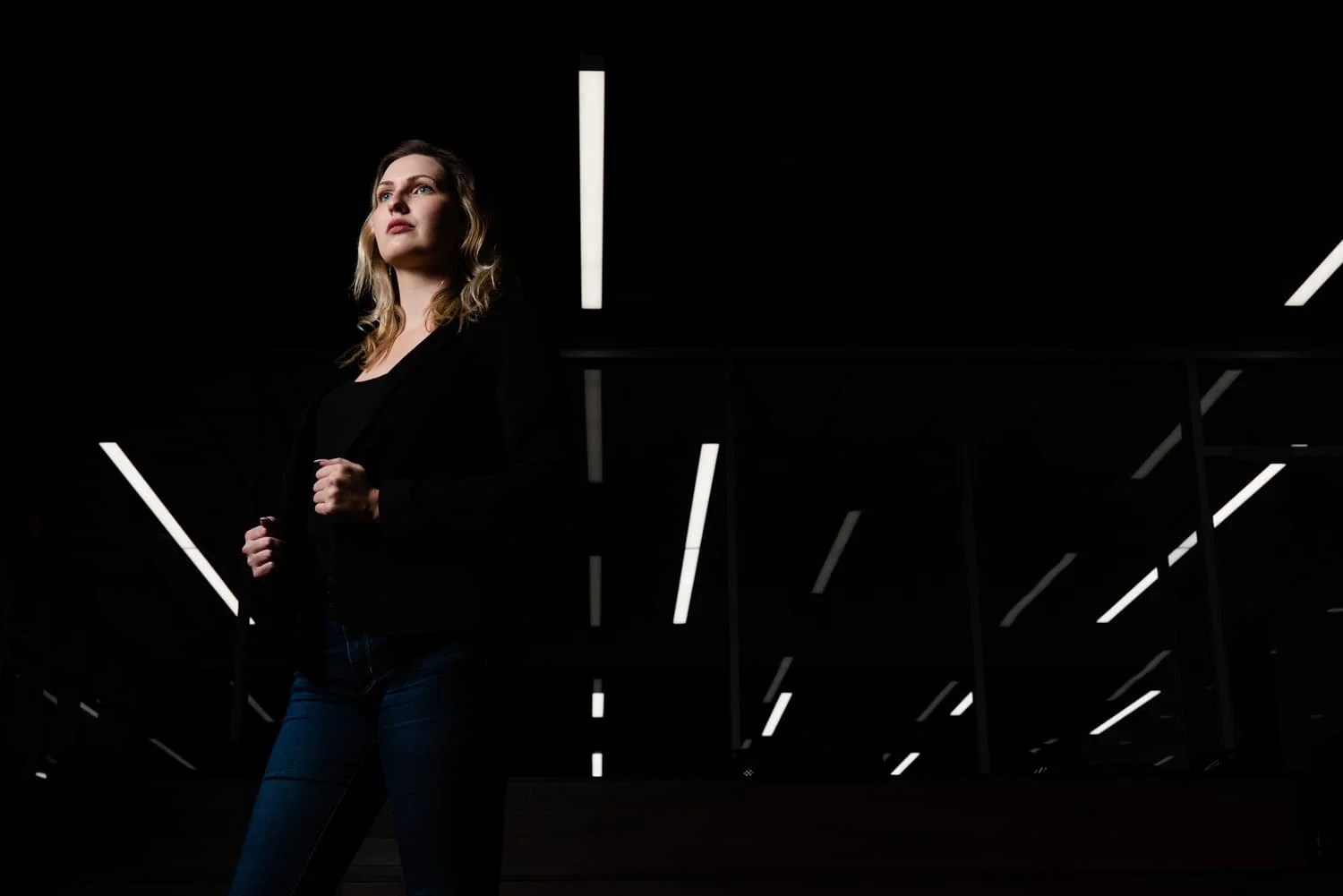 student standing looking off with lights in background