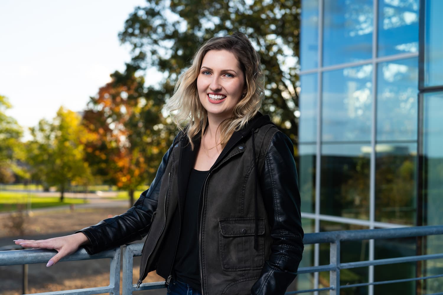  student smiling in front of trees and building outside 