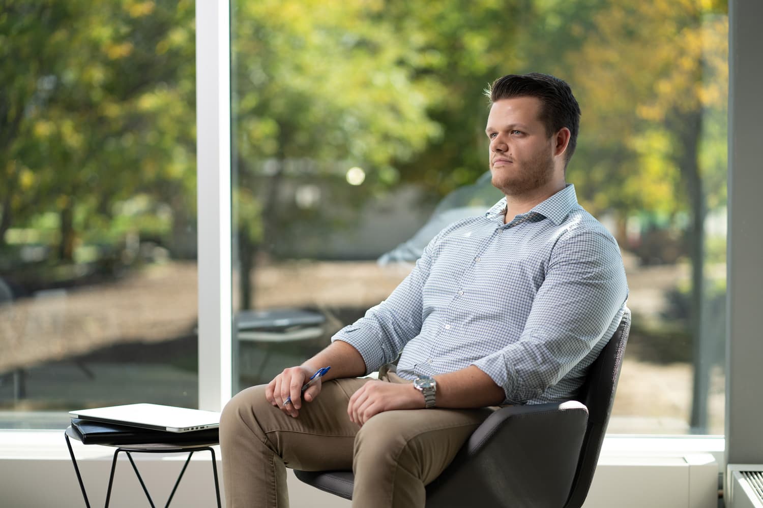  student sitting in chair with trees showing through the windows 