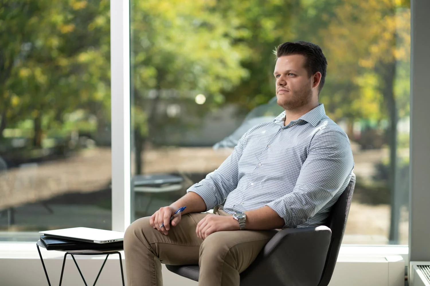 student sitting in chair with trees showing through the windows