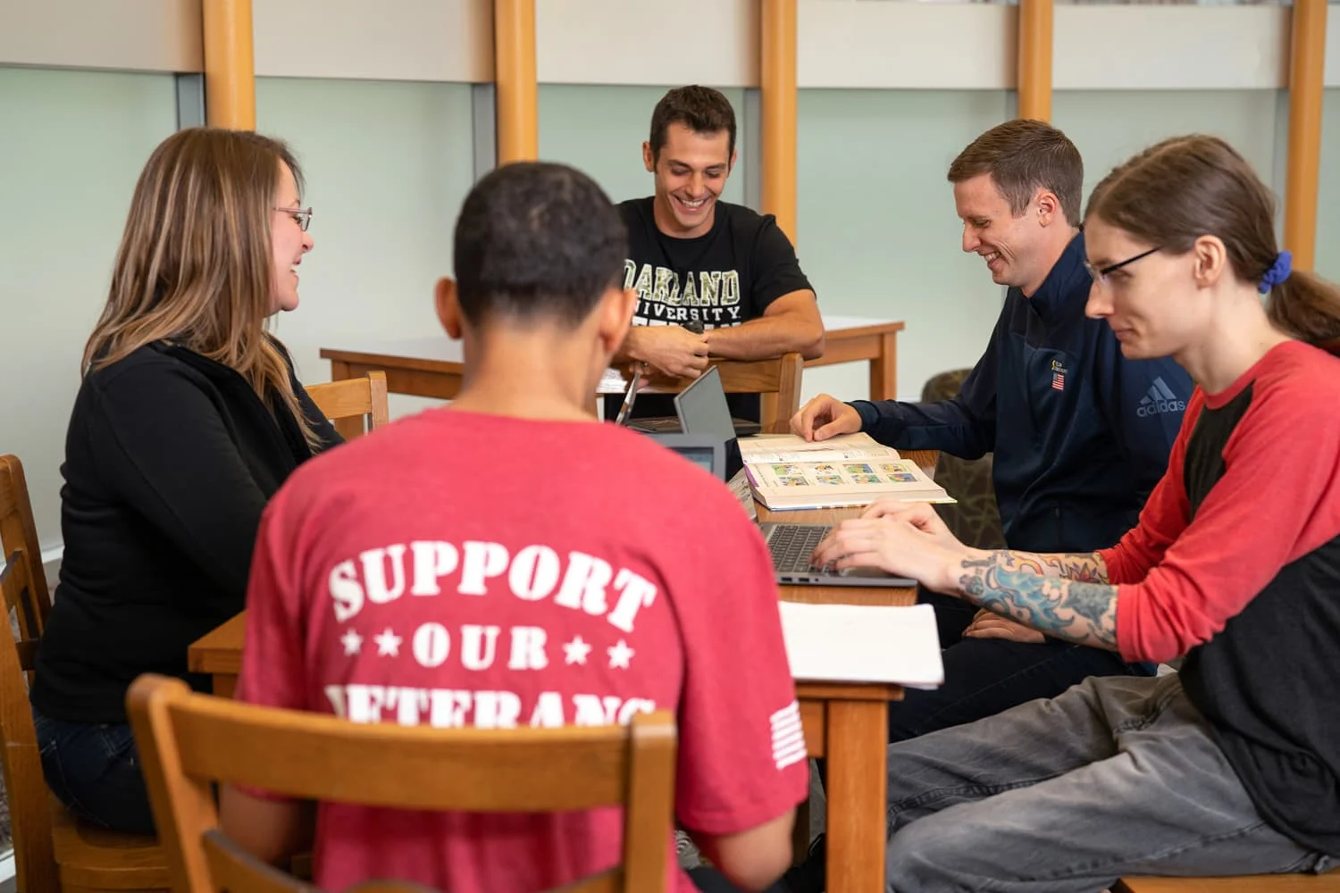 5 students gathered around table laughing