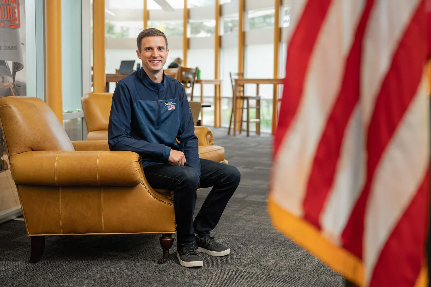 student in chair with american flag in foreground