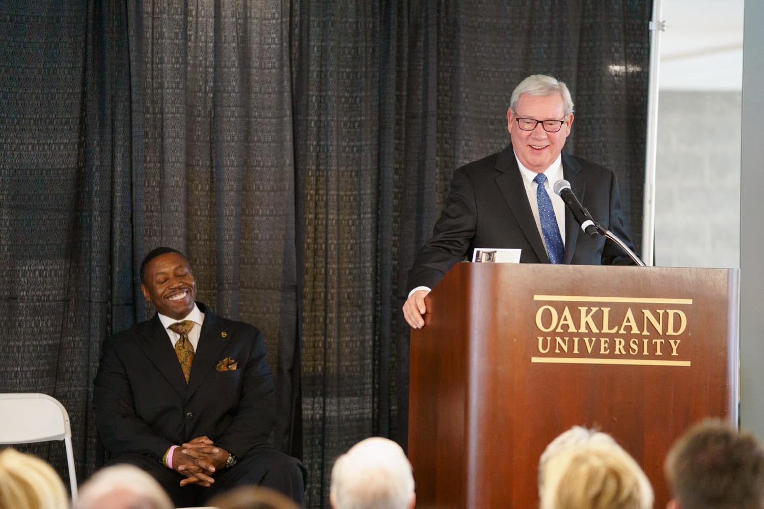  man in suit speaking at podium 