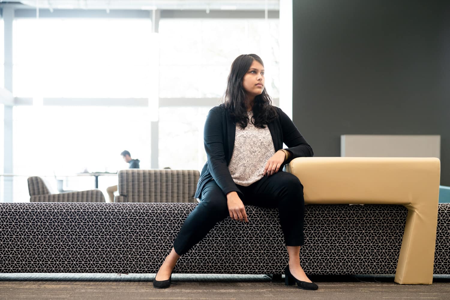  student sitting on bench in grey room 