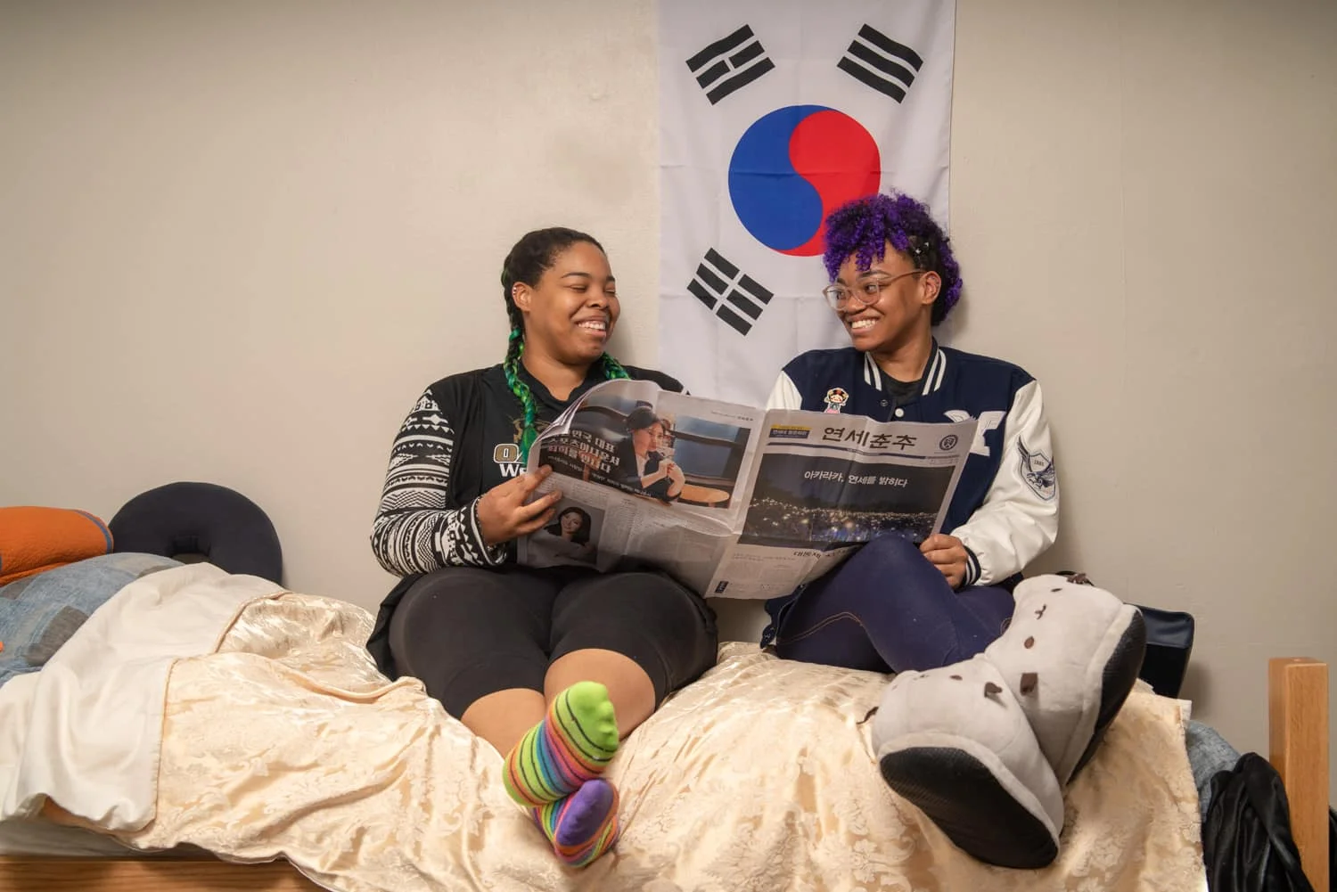two students laughing while reading the newspaper