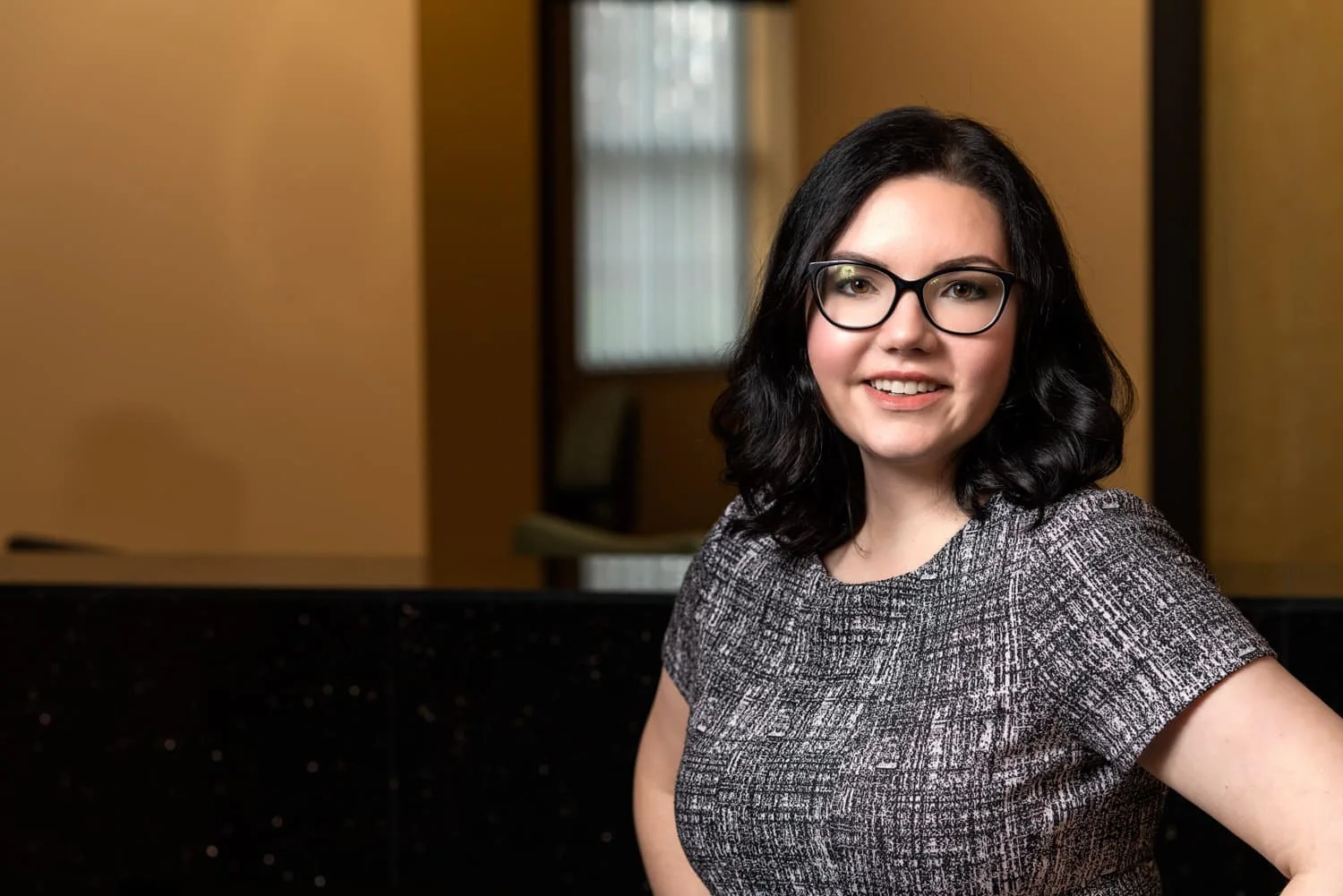headshot portrait of woman with black hair and glasses