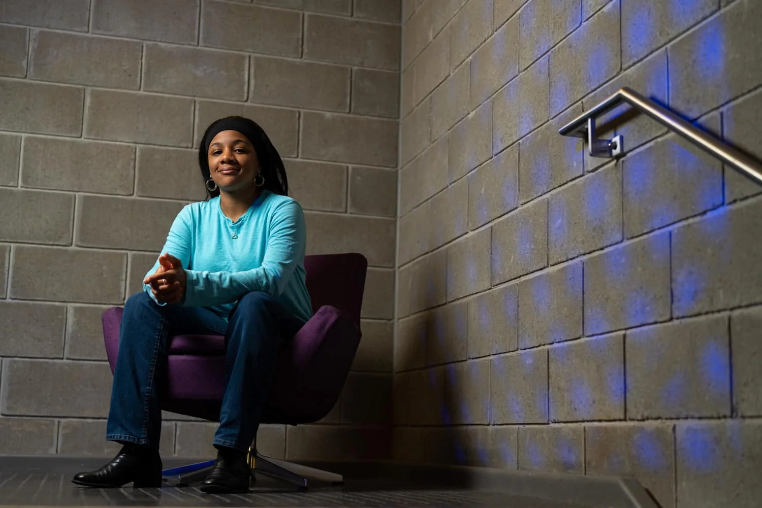 student sitting in chair in front of brick wall
