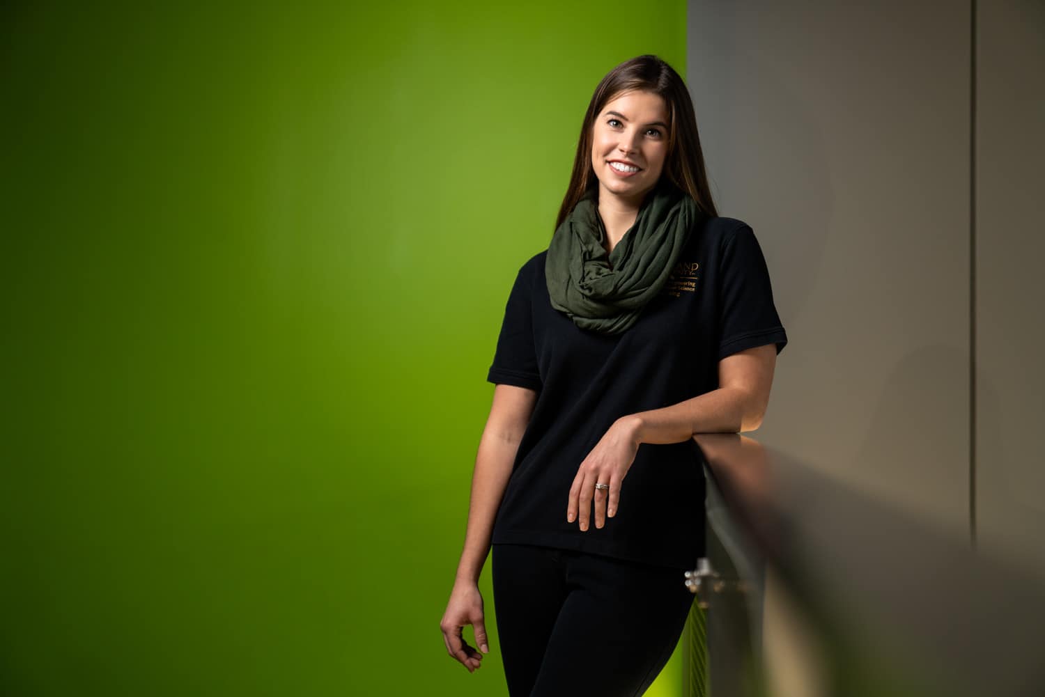  woman leaning on railing in front of green wall 