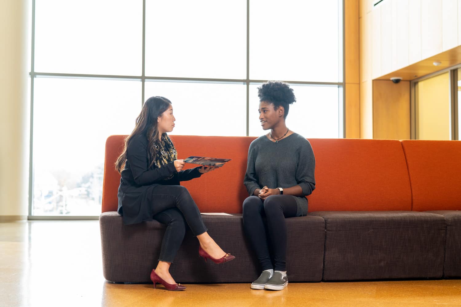  student and advisor discussing paperwork on couch 