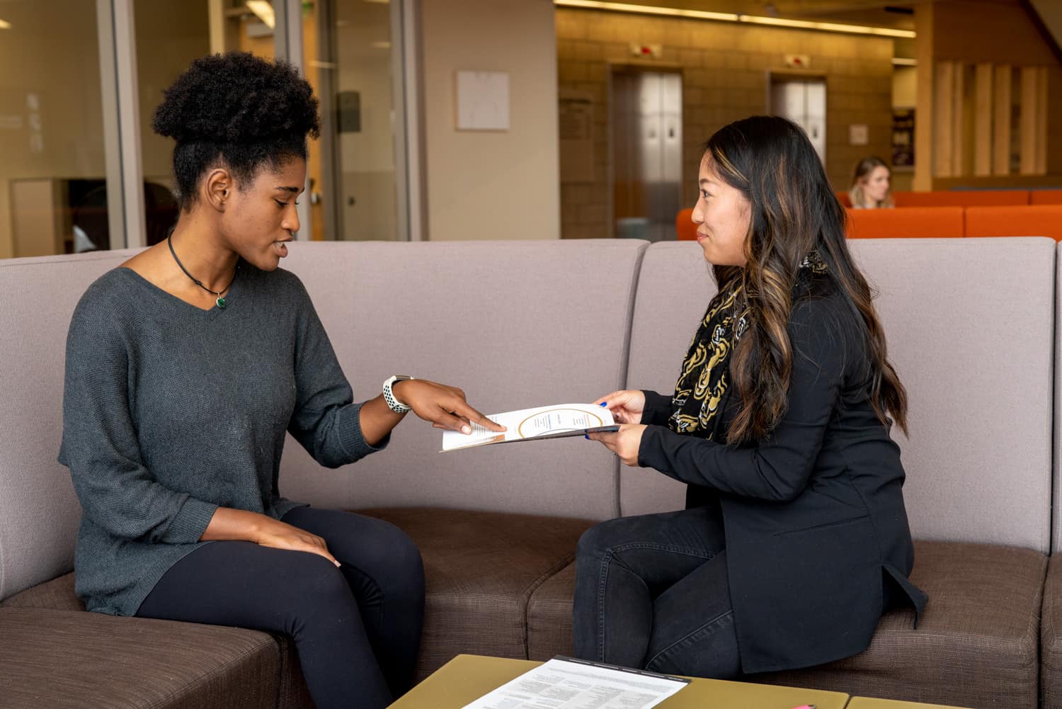  student and advisor discussing paperwork on couch 