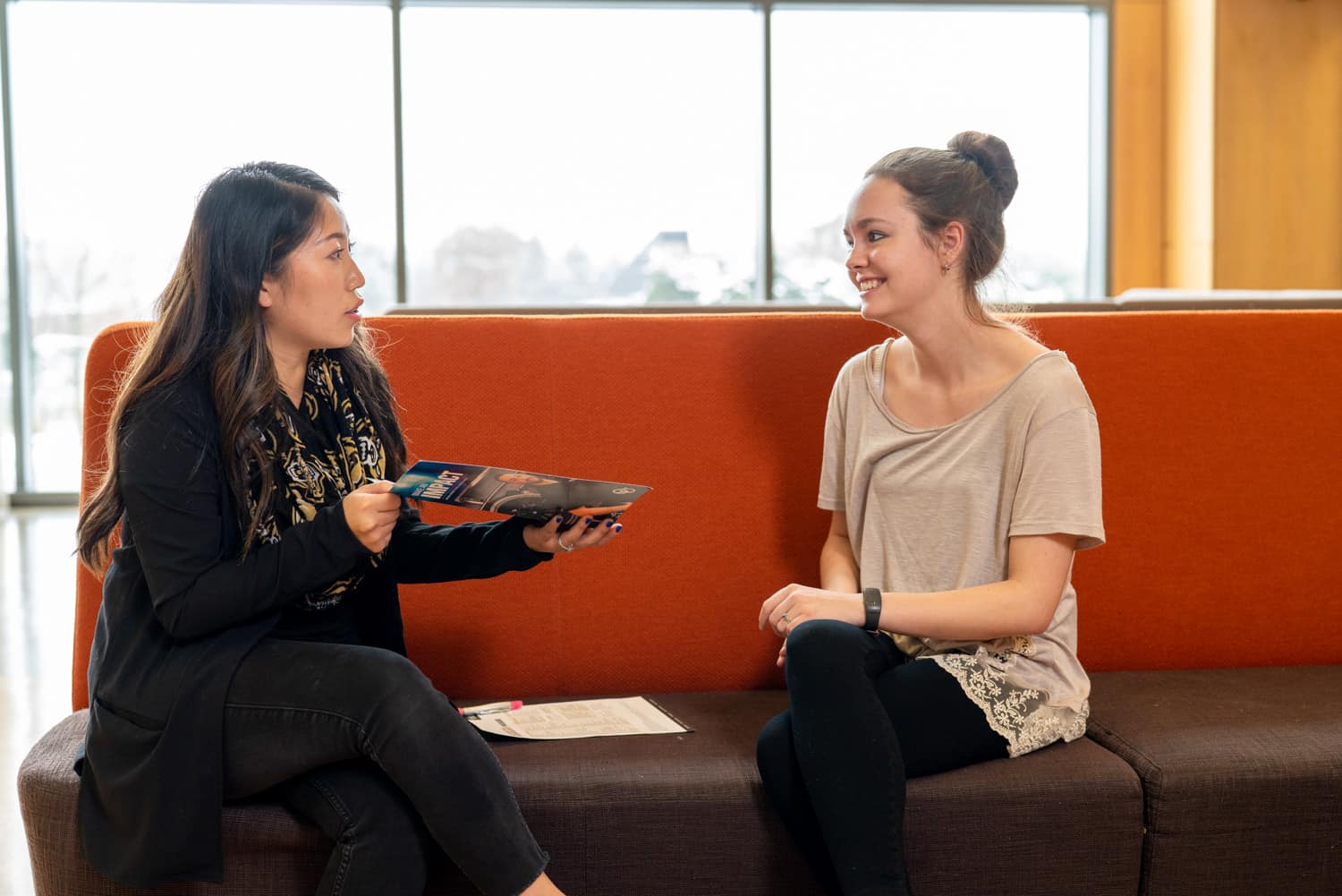  student and advisor discussing paperwork on couch 