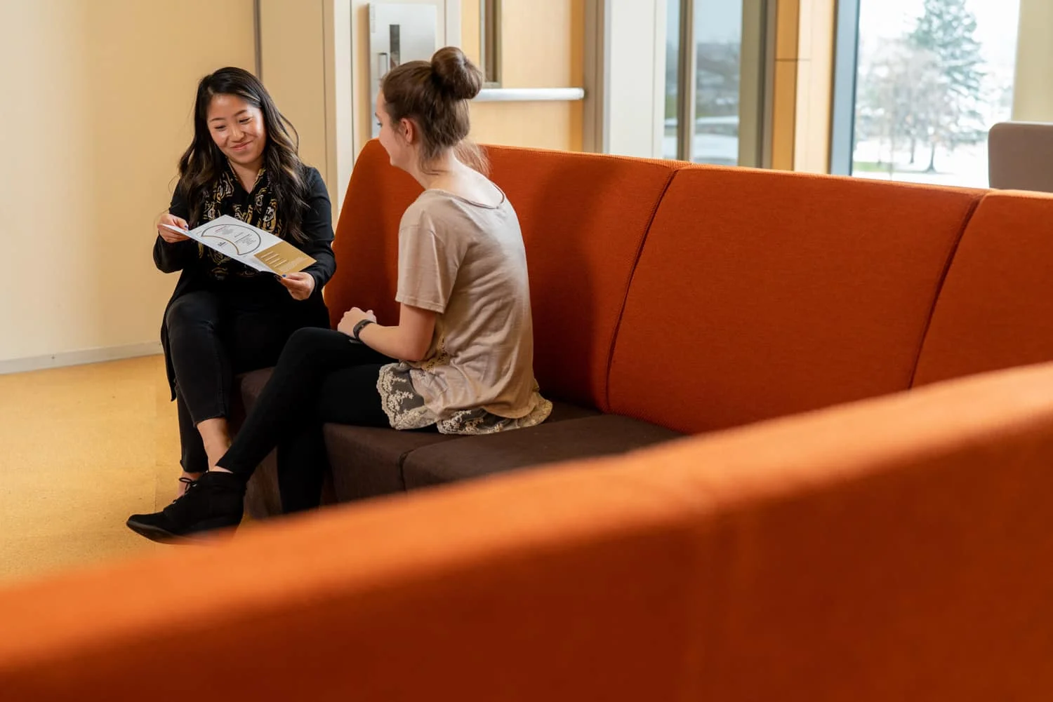 student and advisor discussing paperwork on couch