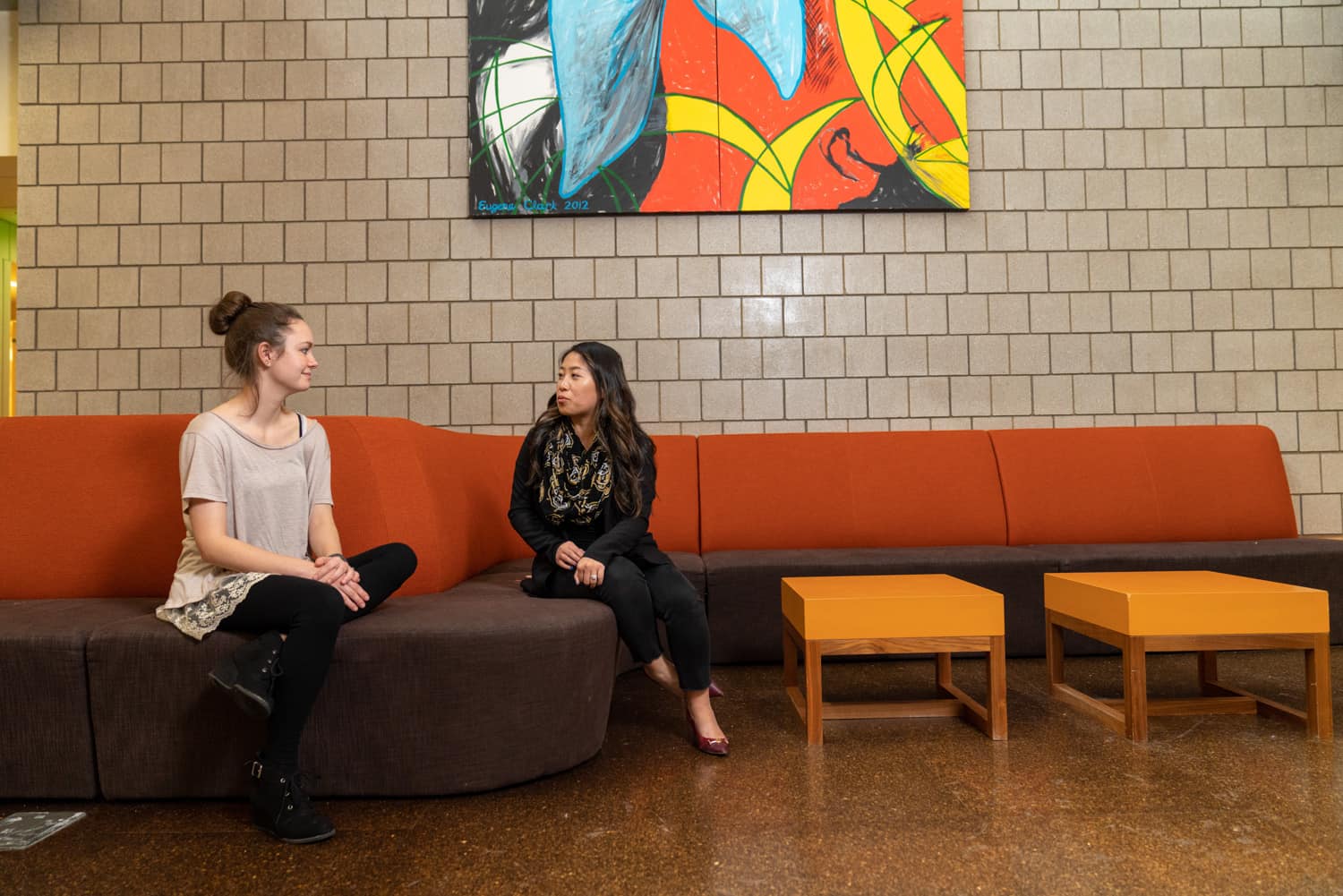  student and advisor discussing paperwork on couch 