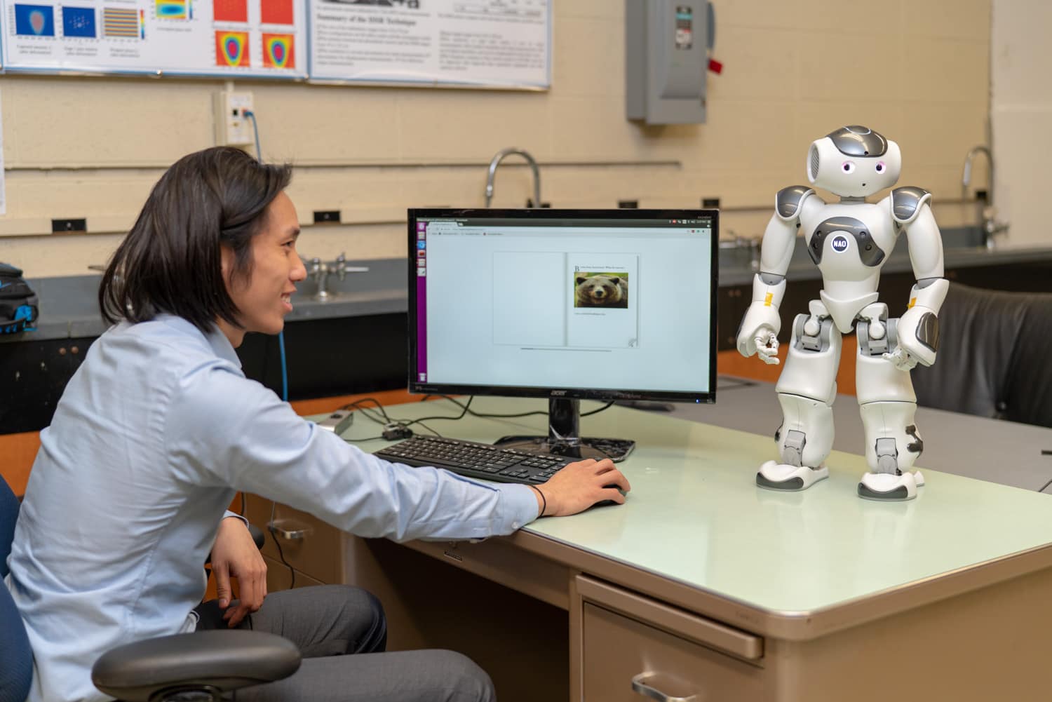  student working on computer controlling small robot 