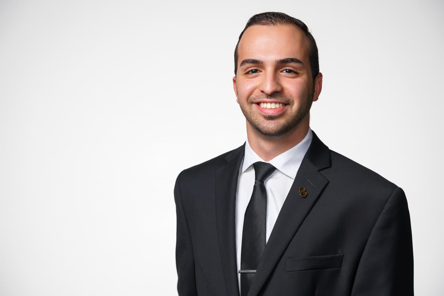  portrait of student in black suit with white shirt and black tie. 