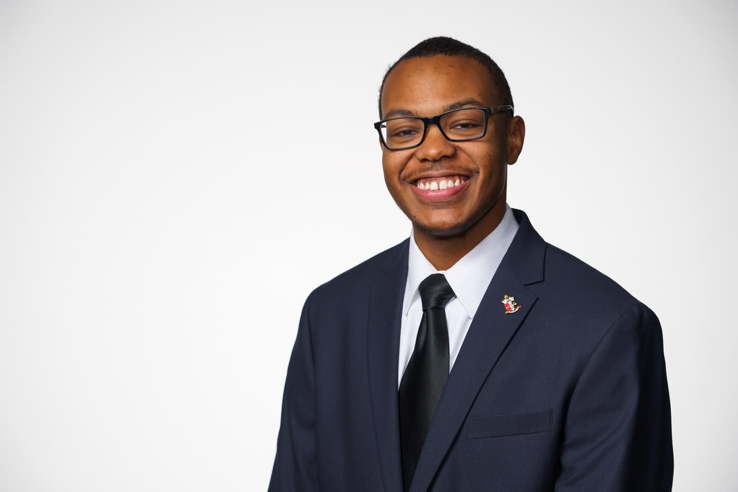  portrait of student in white shirt navy jacket and black tie 