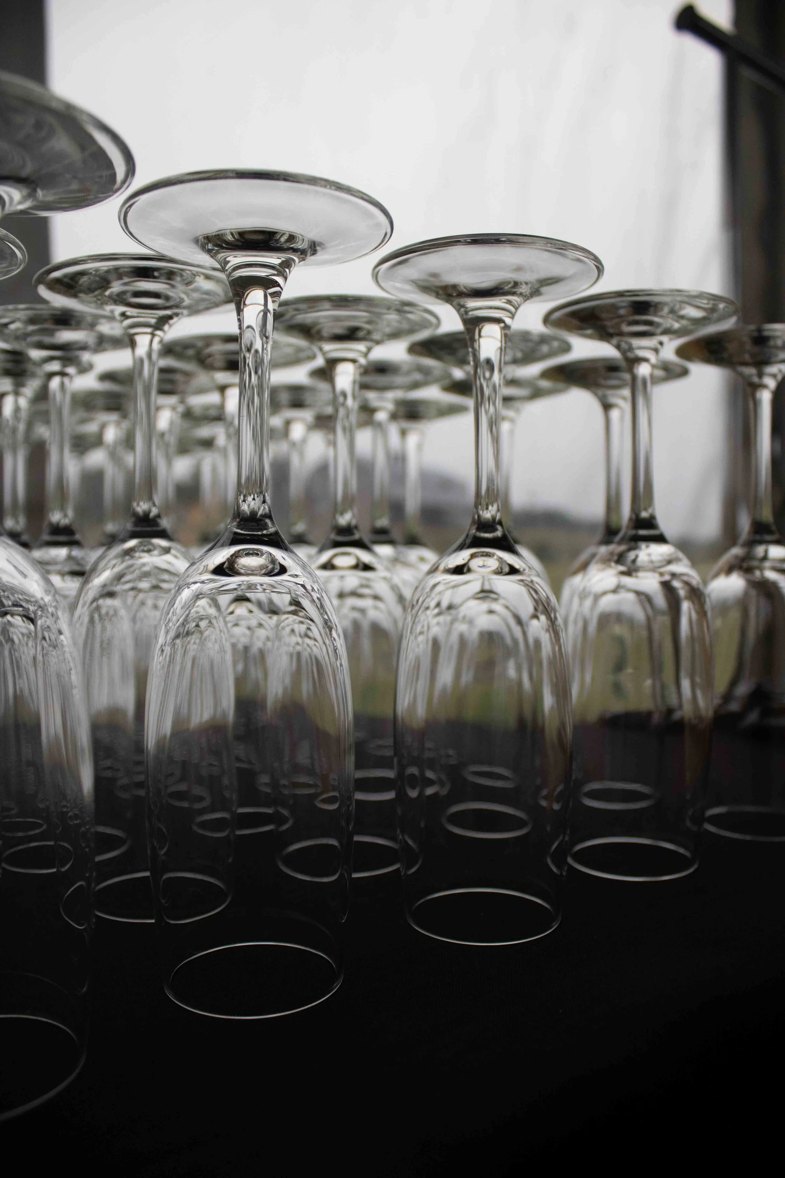 Multiple empty wine glasses placed upside down on a black surface, with a light background.