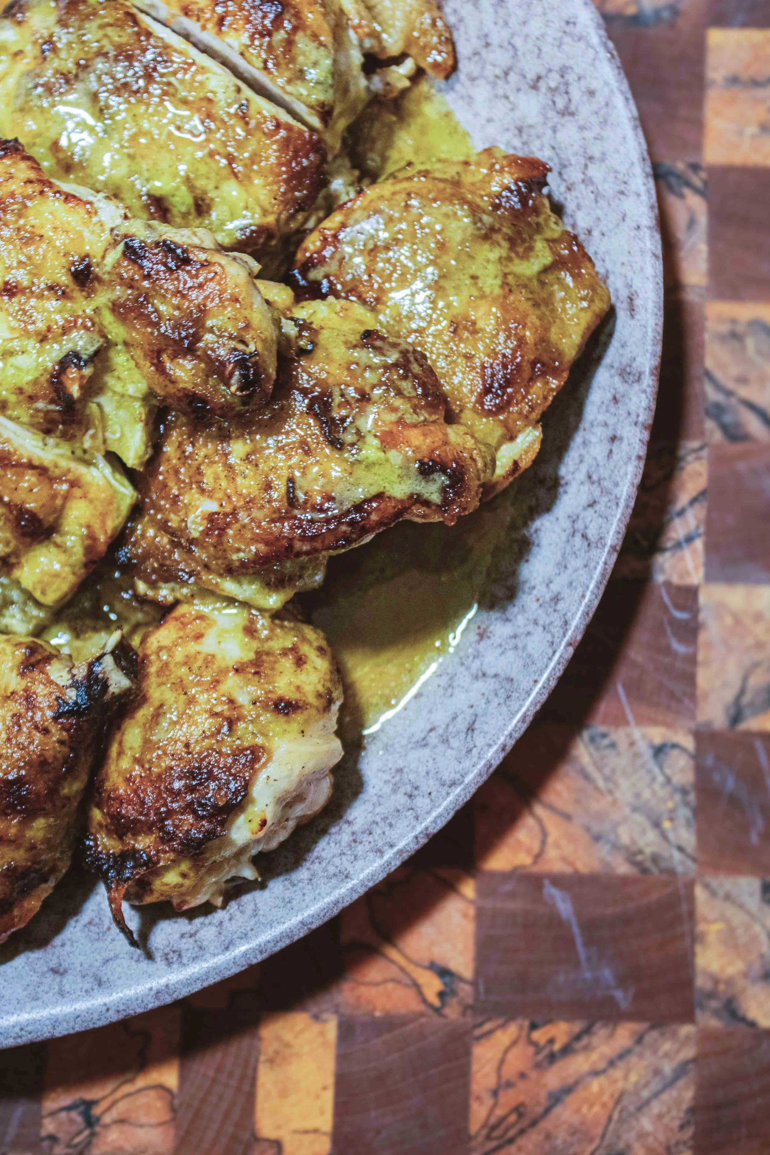 Close-up view of cooked chicken pieces with golden-brown crispy skin in a bowl.