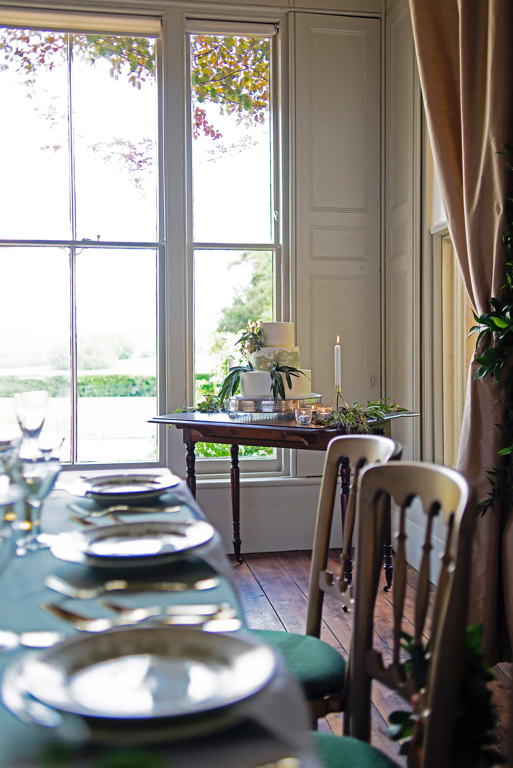 Table setting at Nurstead Court Wedding Venue, Kent with Eucalyptus foliage 3 tier wedding cake by Cakes & Leaves.