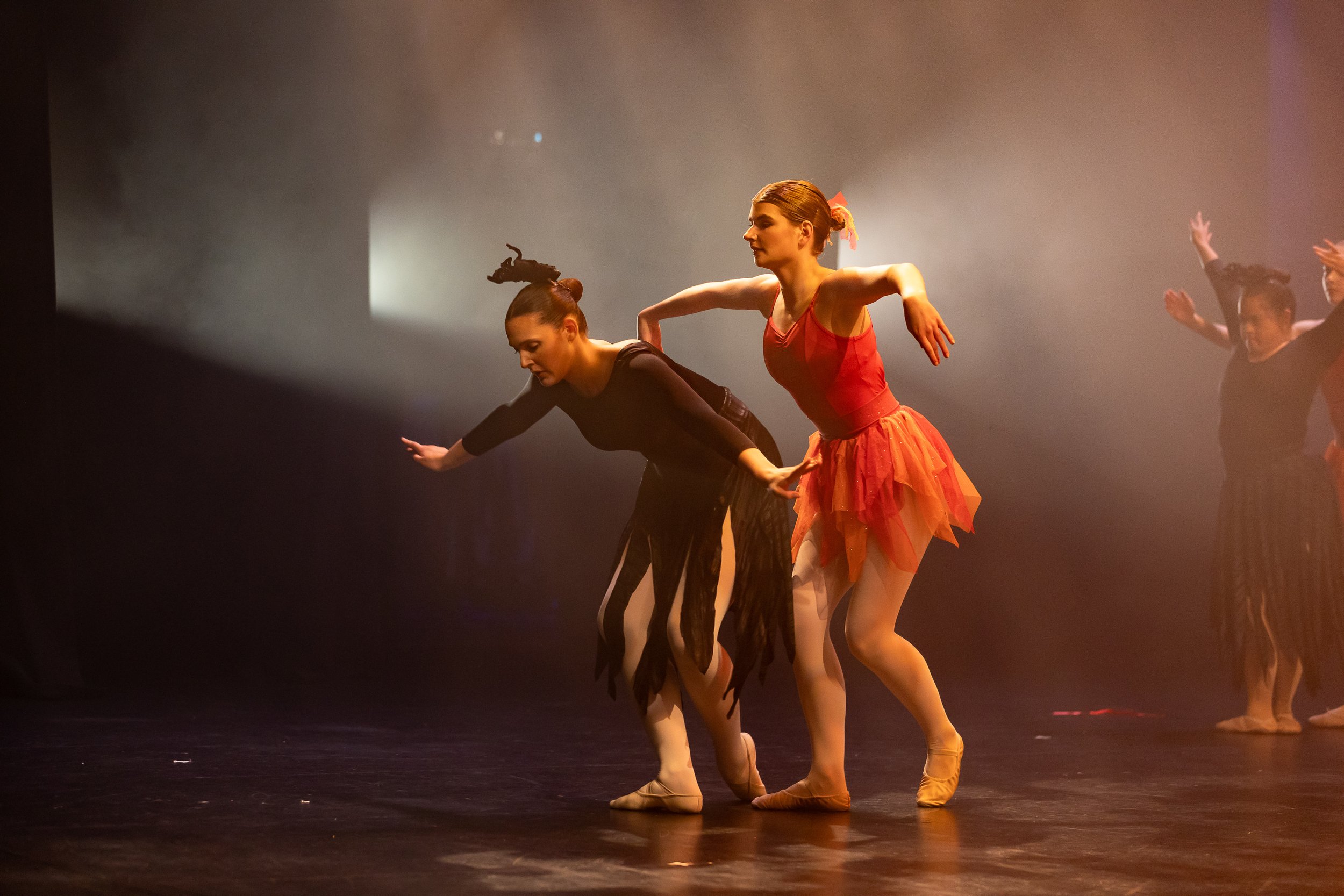 Ballet dancers performing on stage with dramatic lighting, wearing colorful costumes, and practicing ballet poses.